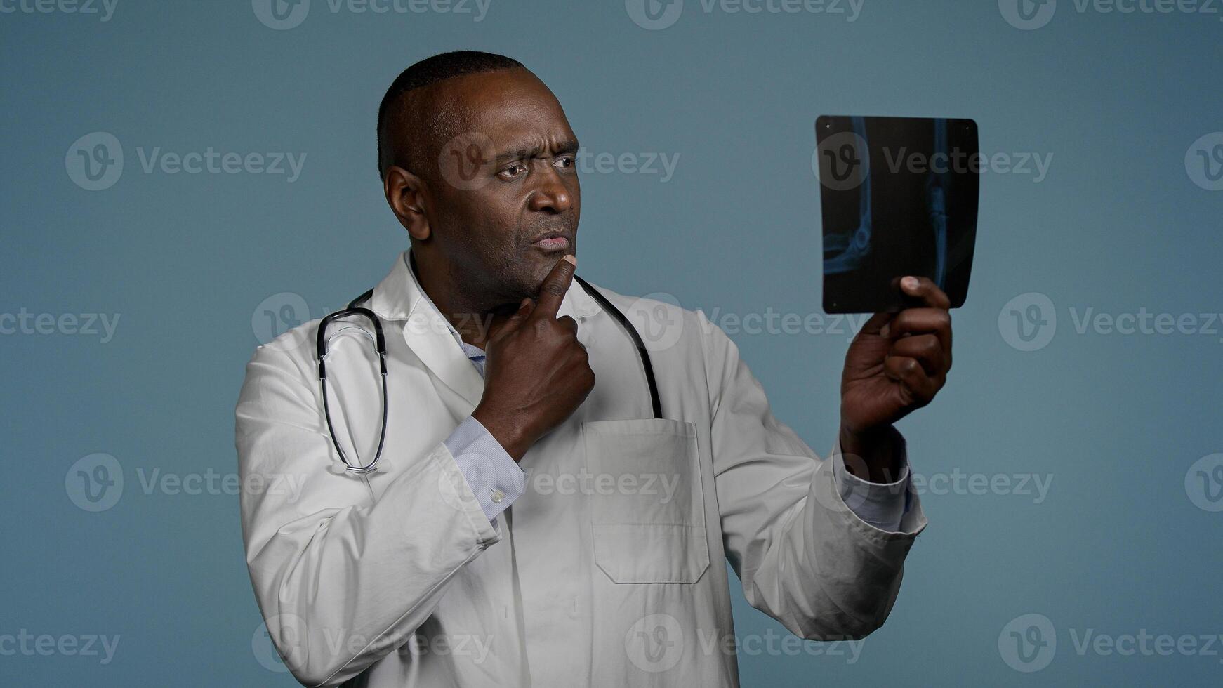 Mature serious man radiologist doctor examining x-ray check results scan looking pensive and focused upset male medic expert surgeon analyzes injury on tomography image makes bad diagnosis fracture photo