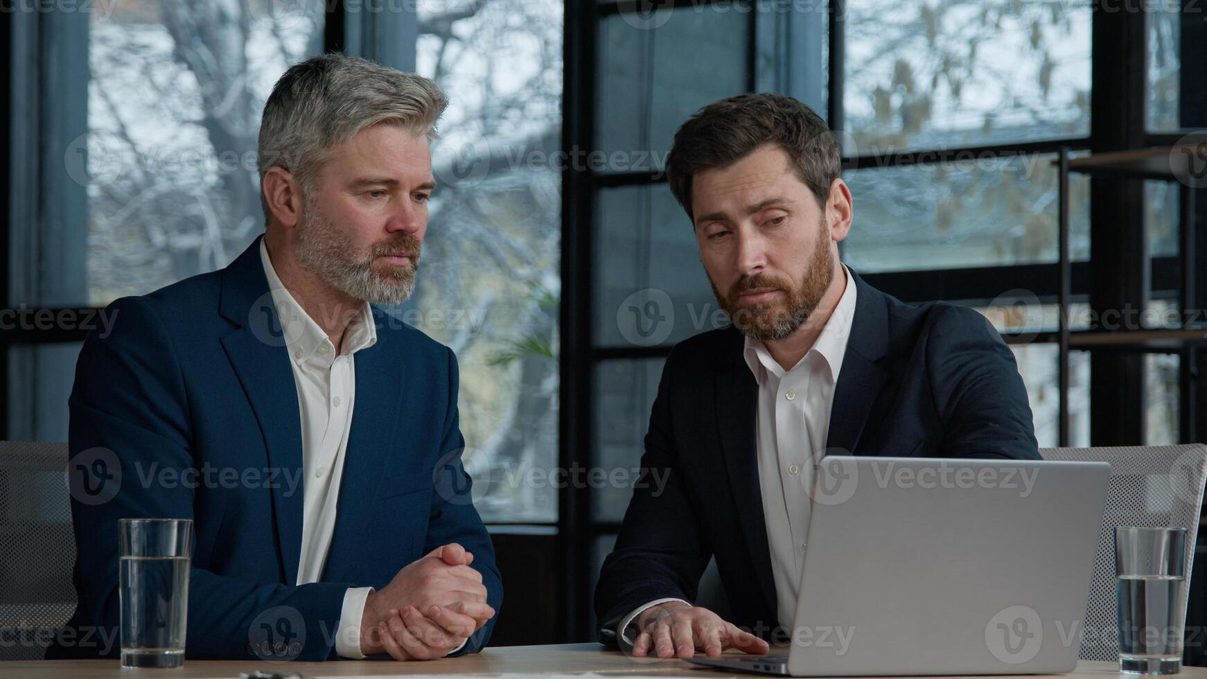 Caucasian men businessmen partners client consultant talking at business meeting in office viewing online project on laptop discussing deal profitable contract shaking hands handshaking cooperation photo