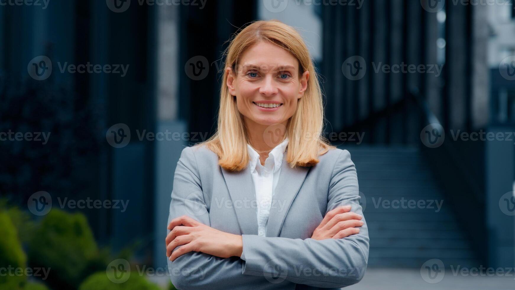 Caucasian woman walking outdoors successful confident businesswoman professional manager leader entrepreneur corporate employee posing with arms crossed on street near office building looks at camera photo