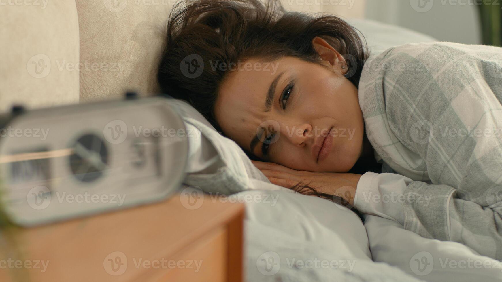 Woman sleeping lying on bed bedroom home domestic comfort early morning call alarm clock wake up turn off continue sleep napping slumber drowsy girl female tired dissatisfied time awake digital device photo