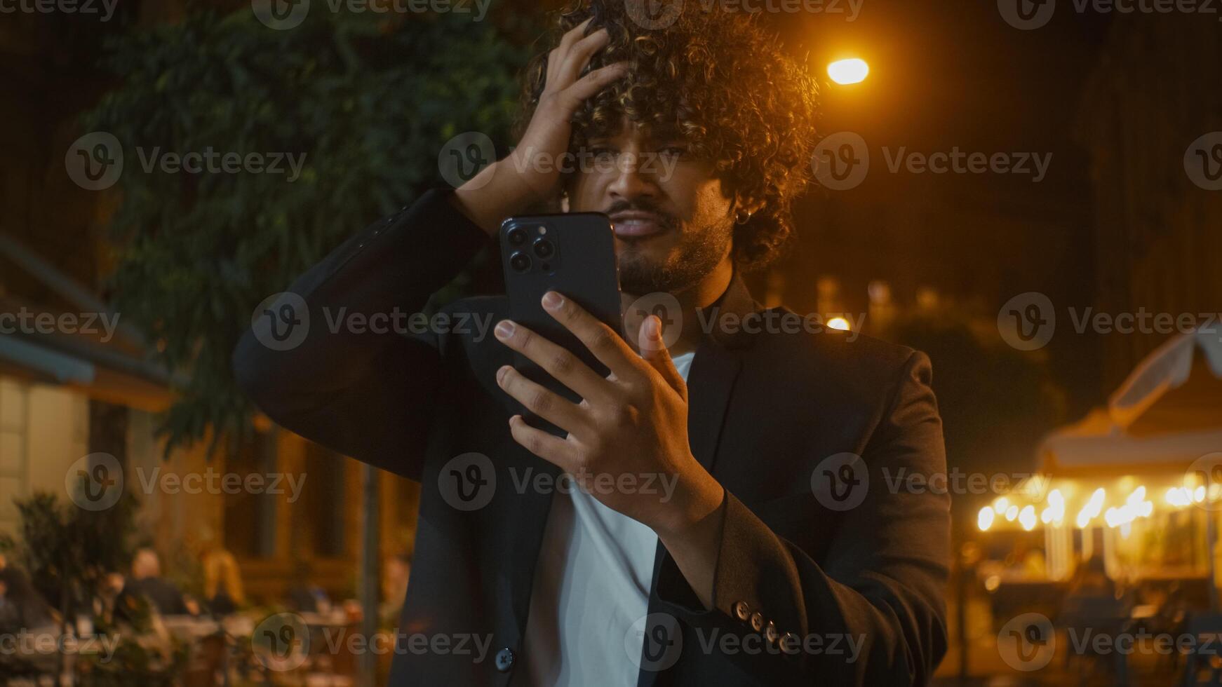 Indian Arabian Latino American man using mobile phone smartphone losing failure bad news messages annoyed dissatisfied unhappy guy hold head city outside evening mistake problem trouble breaking gen z photo