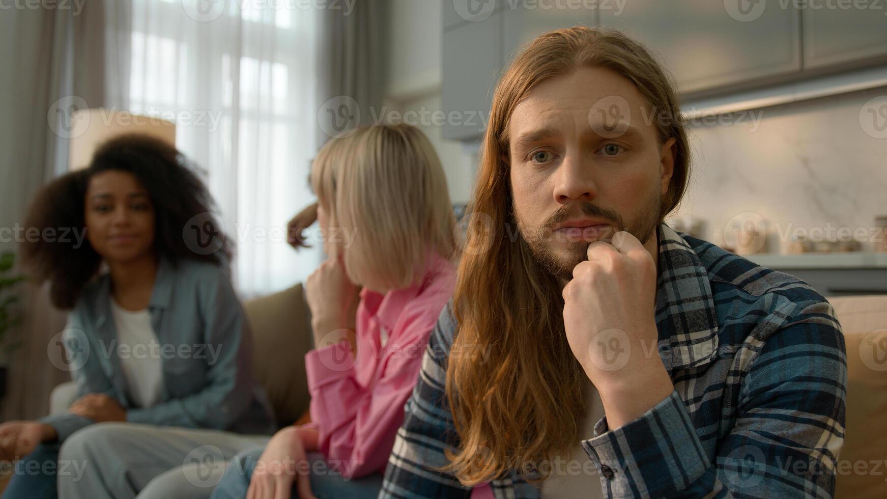 Upset offended Caucasian man male guy thinking anxiety worried think suffer at home feel lonely excluded ignoring friends talking multiracial fun people women men Caucasian buddies introvert avoiding photo