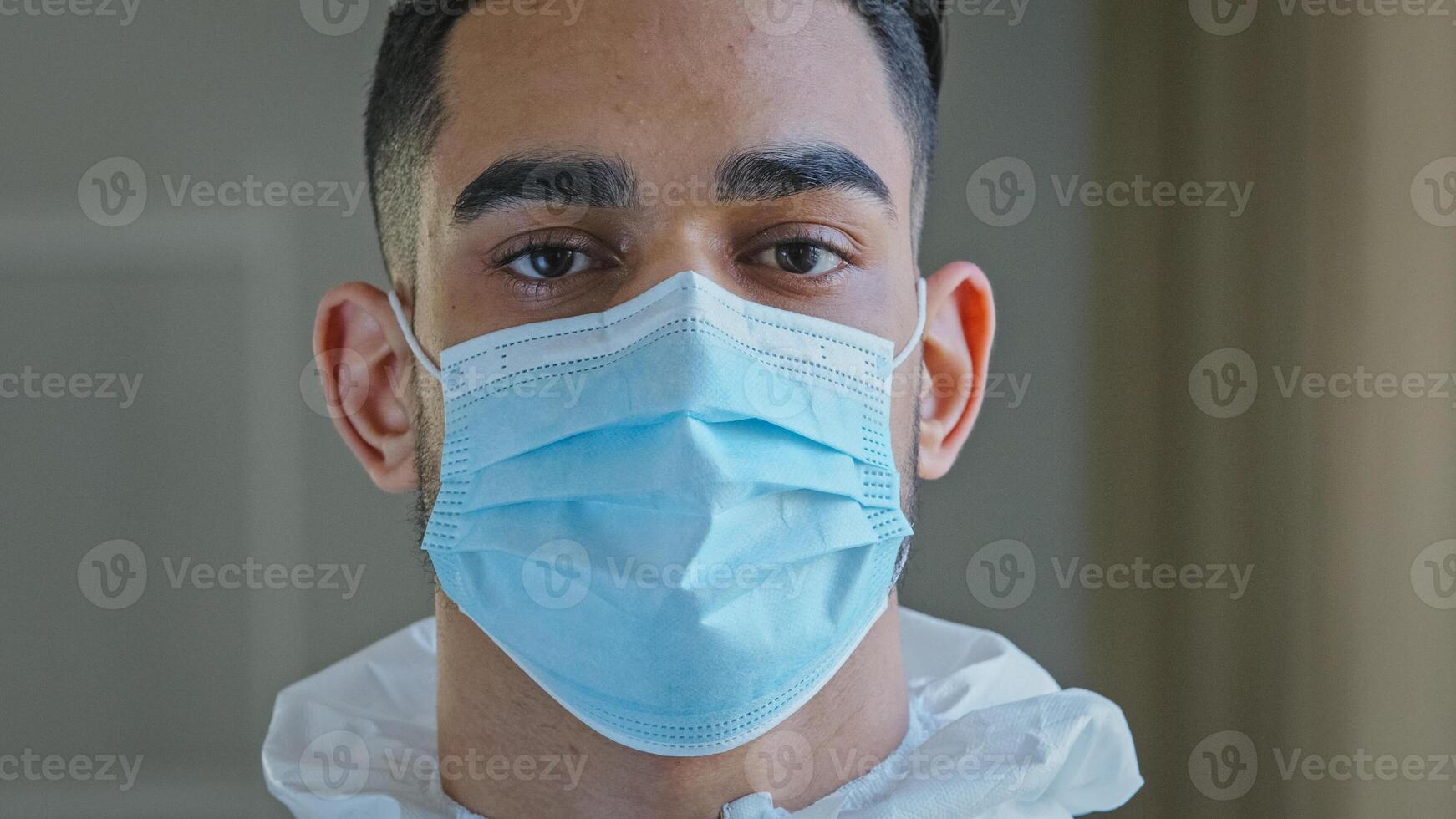 Portrait sad male face tired ethnic arabic hispanic doctor man medical worker surgeon specialist wear protective mask during pandemic corona in hospital looking at camera after complicated operation photo