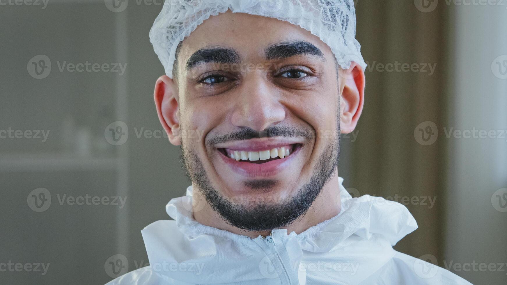 Smiling doctor arabic surgeon hispanic nurse medical worker in special uniform hat looks at camera smile toothy after successful operation working with coronavirus enjoying end of covid-19 pandemic photo