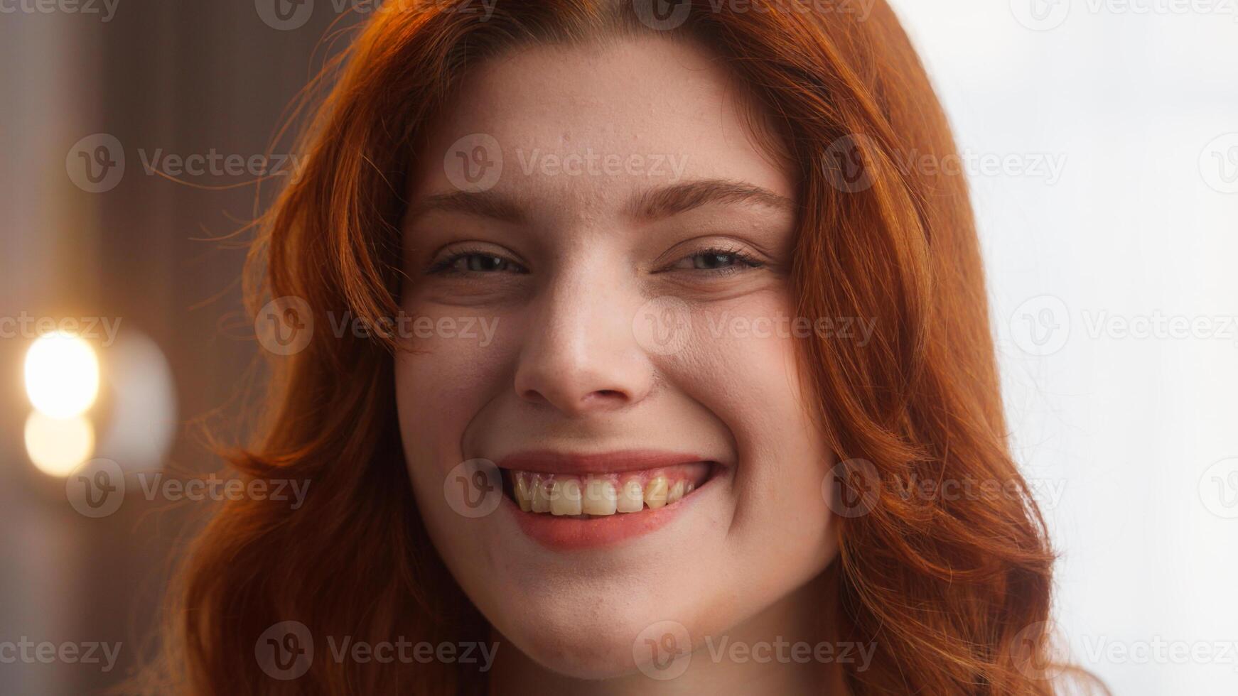 Attractive happy Caucasian woman close up carefree female pretty lady look at camera winking playful gesture joy emotion sign blink charming redhead girl smile with perfect white teeth posing at home photo