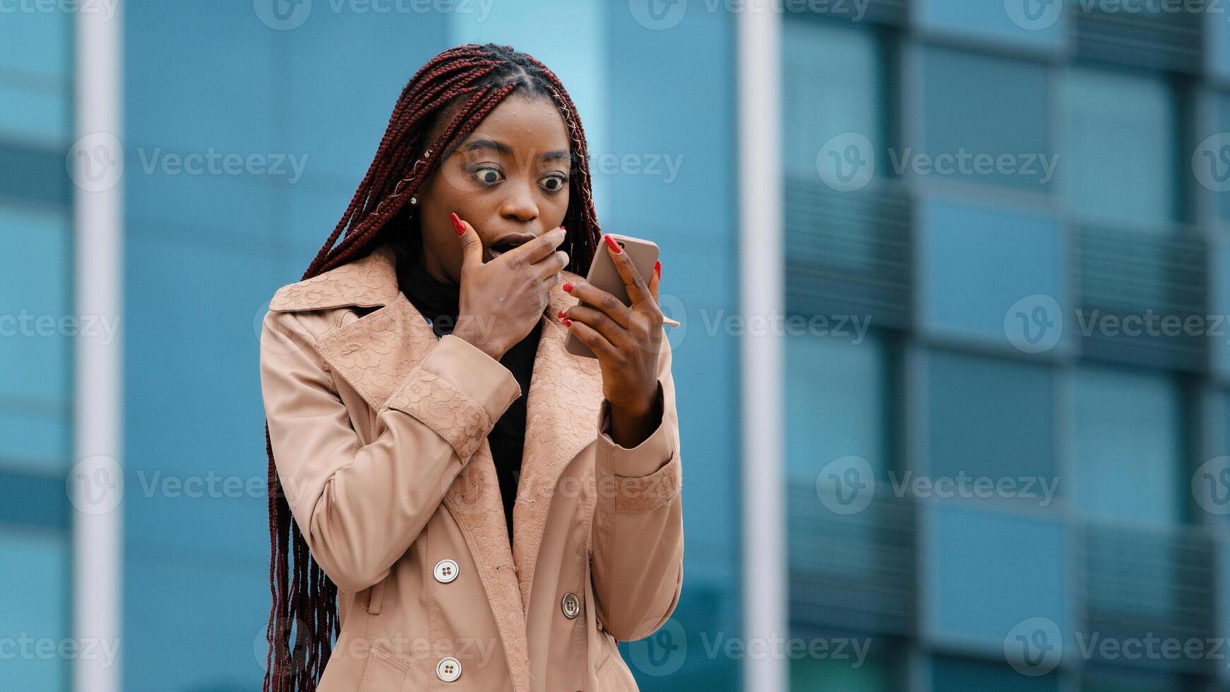 Excited enthusiastic surprised african american woman winner outdoors reading good news on phone celebrating victory rejoicing in success winning lottery receives notification on smartphone side view photo