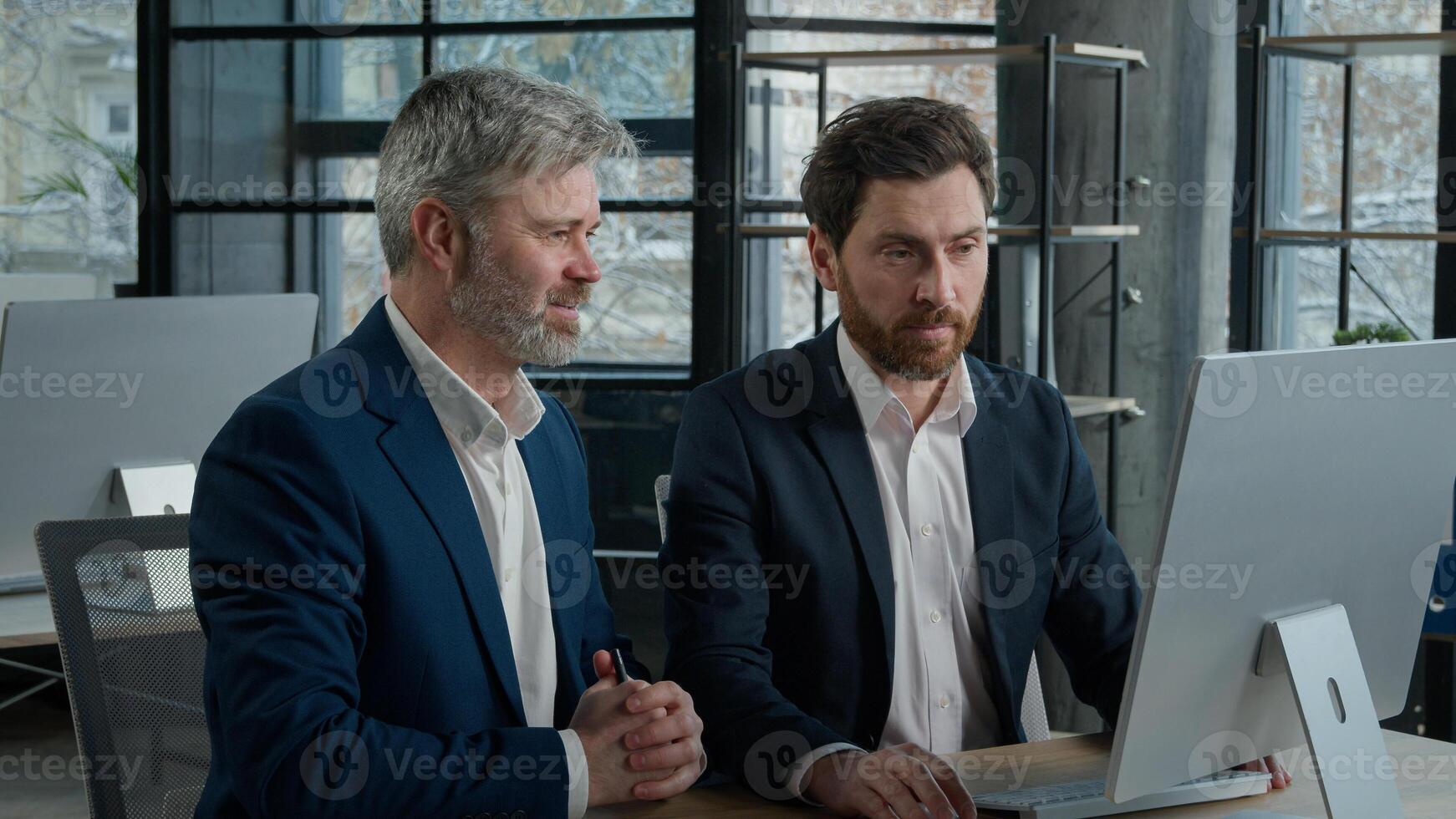 Two surprised happy Caucasian businessmen men business partner employees colleagues looking computer screen celebrating victory win patent rejoicing at achievement successful deal high sales growth photo
