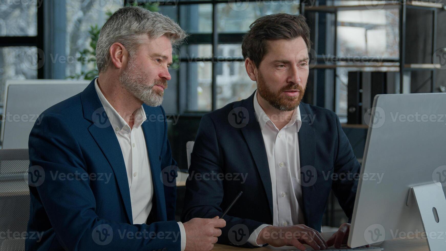 Mature businessman mentoring man discussing project on computer consulting investor client about digital investment in office Caucasian businessmen colleagues working together discuss data management photo