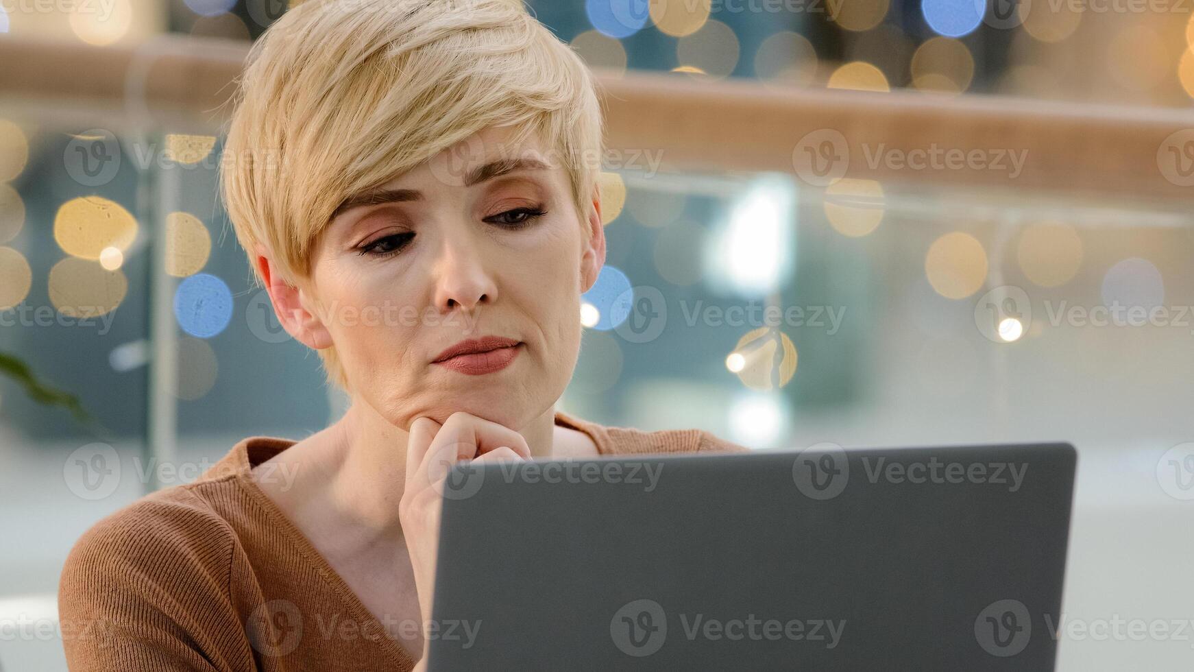 Thoughtful serious doubtful smart middle aged adult 40s woman pensive lady looking away thinking future vision solving problem difficult question business challenges working with laptop feeling doubt photo