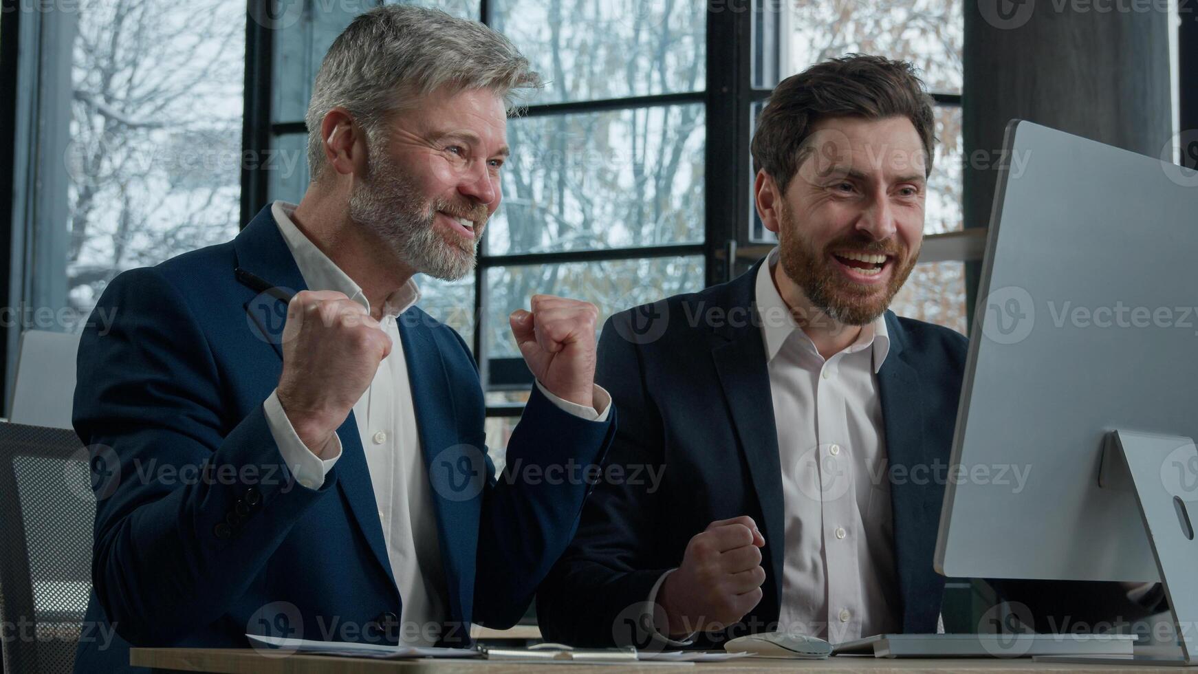 Two businessmen men business partner colleagues collaboration in office working on computer brainstorm in corporate teamwork get good news win deal celebrating victory in online game rejoice success photo