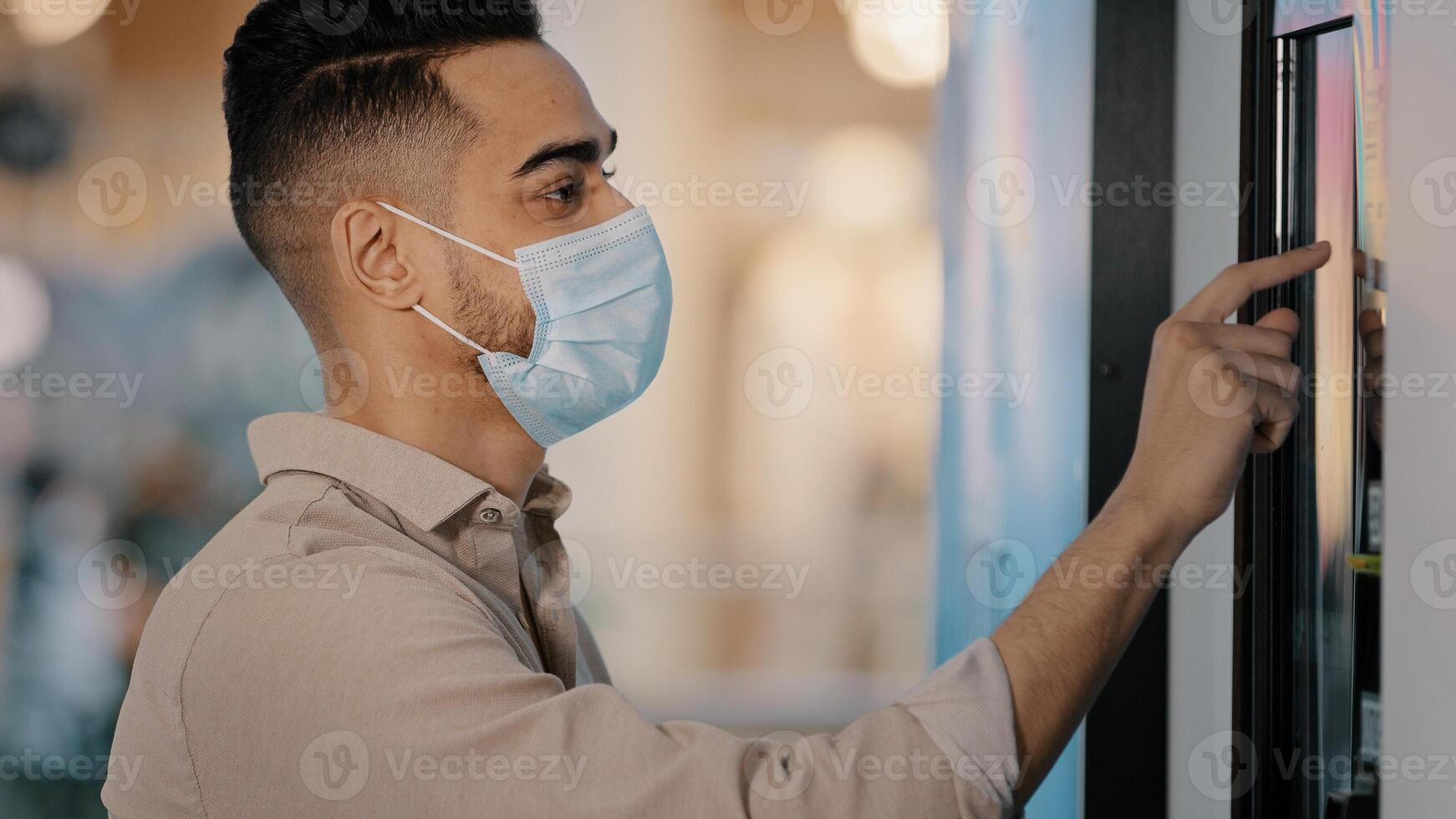 Side view male passenger Indian Hispanic man in medical mask in airport terminal businessman in bank office using self-service machine online payment with auto tech touch screen panel terminal display photo