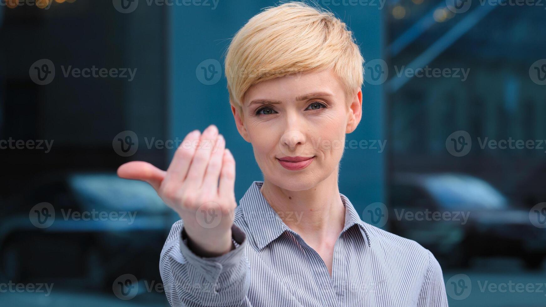 Portrait of beautiful caucasian middle aged adult 40s business woman friendly lady smiling showing gesture of invitation advice to approach herself with hand asks to come outdoors, body languages photo