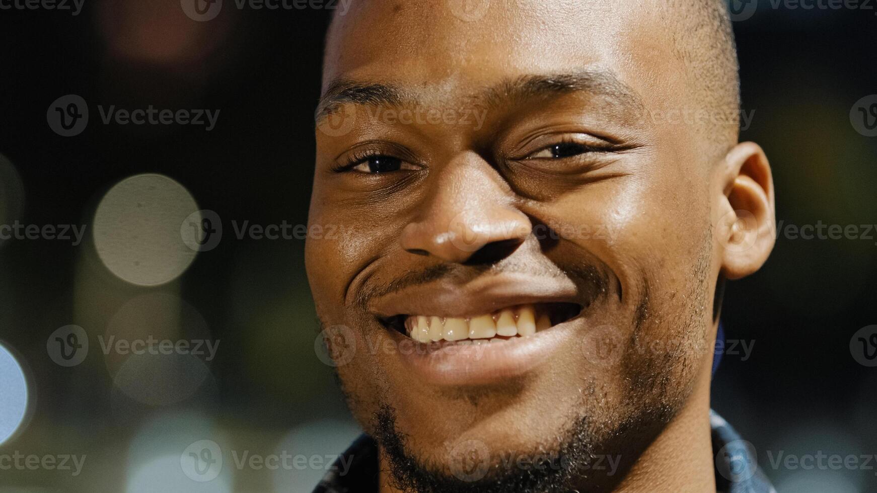 Male happy portrait african american young millennial satisfied man stands in city in evening town lights background looking at camera smiling toothy waving head in agreement answering yes close up photo