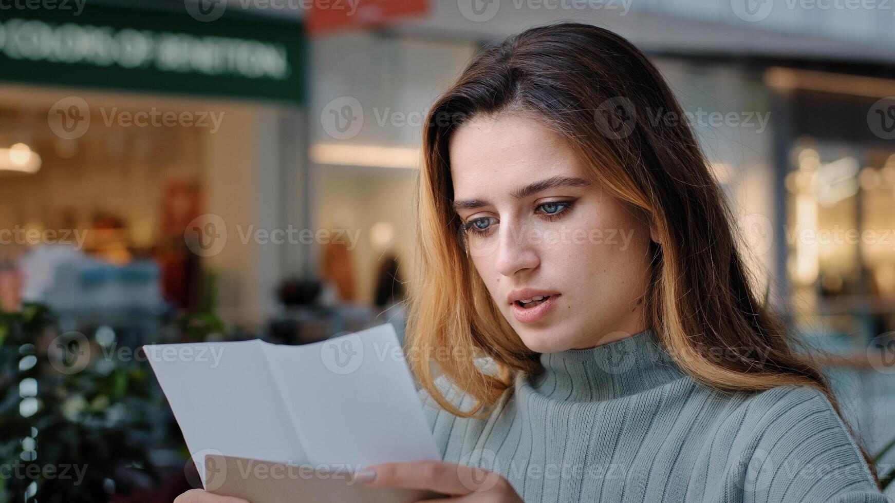 Portrait of beautiful young caucasian millennial woman recipient girl sitting in cafe receiving letter opens envelope reads test results bank notice news from friends new job offer insurance statement photo