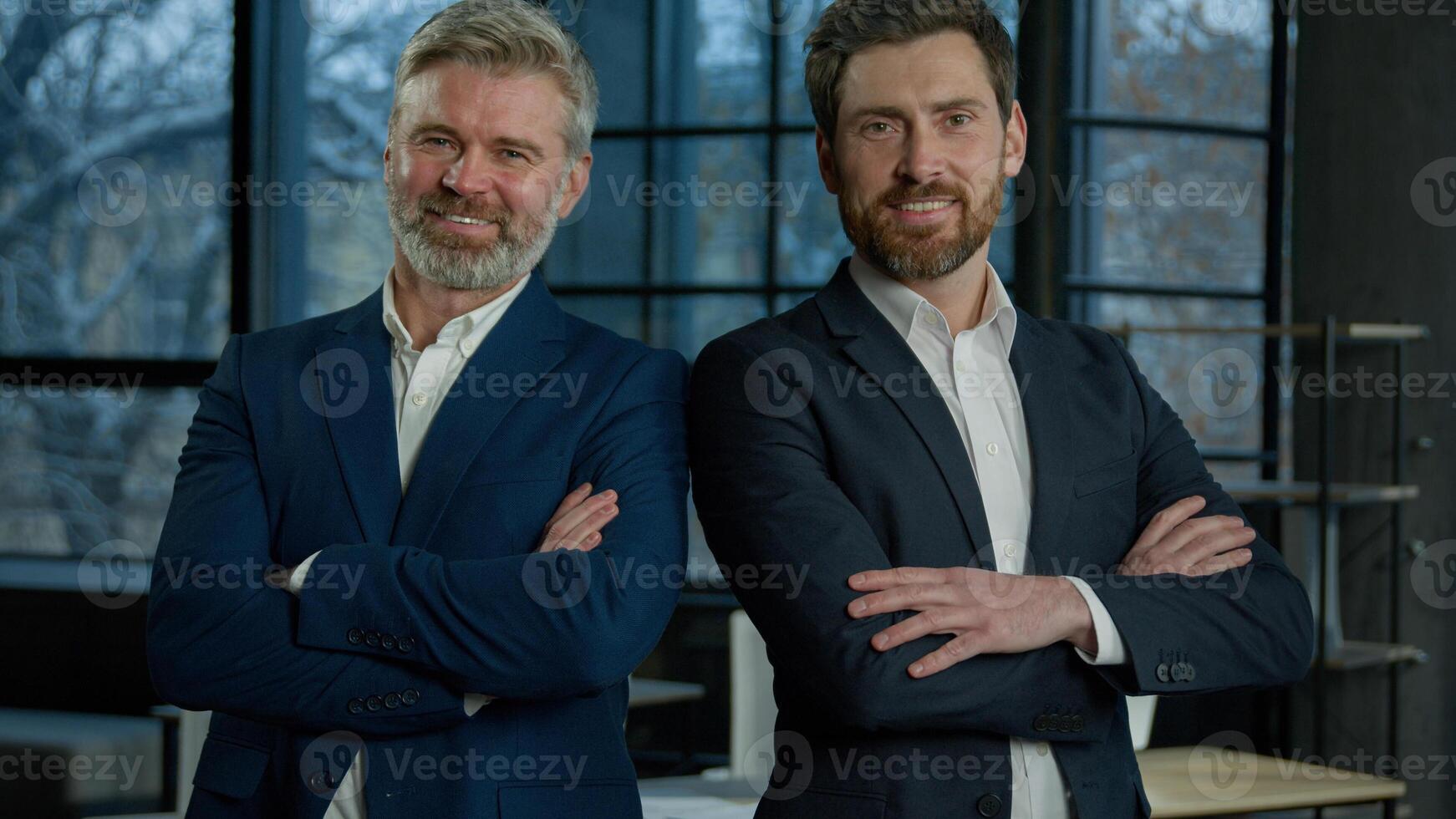 Two successful smiling mature caucasian businessmen entrepreneurs colleagues employees managers leaders business partners posing with arms crossed look camera in office partnership cooperation concept photo
