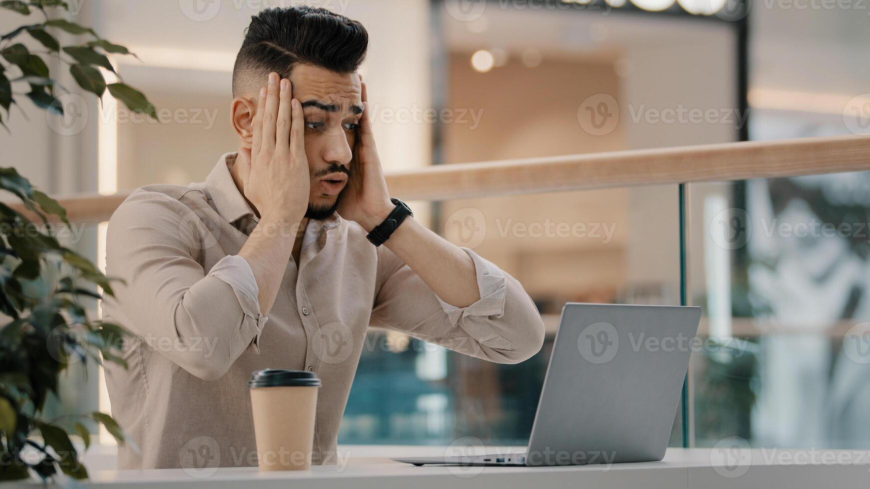 Sad shocked stressed Hispanic Indian man worker manager freelancer entrepreneur manager in cafe has problem with laptop app reading bad news worried with email shock stress business failure lost job photo