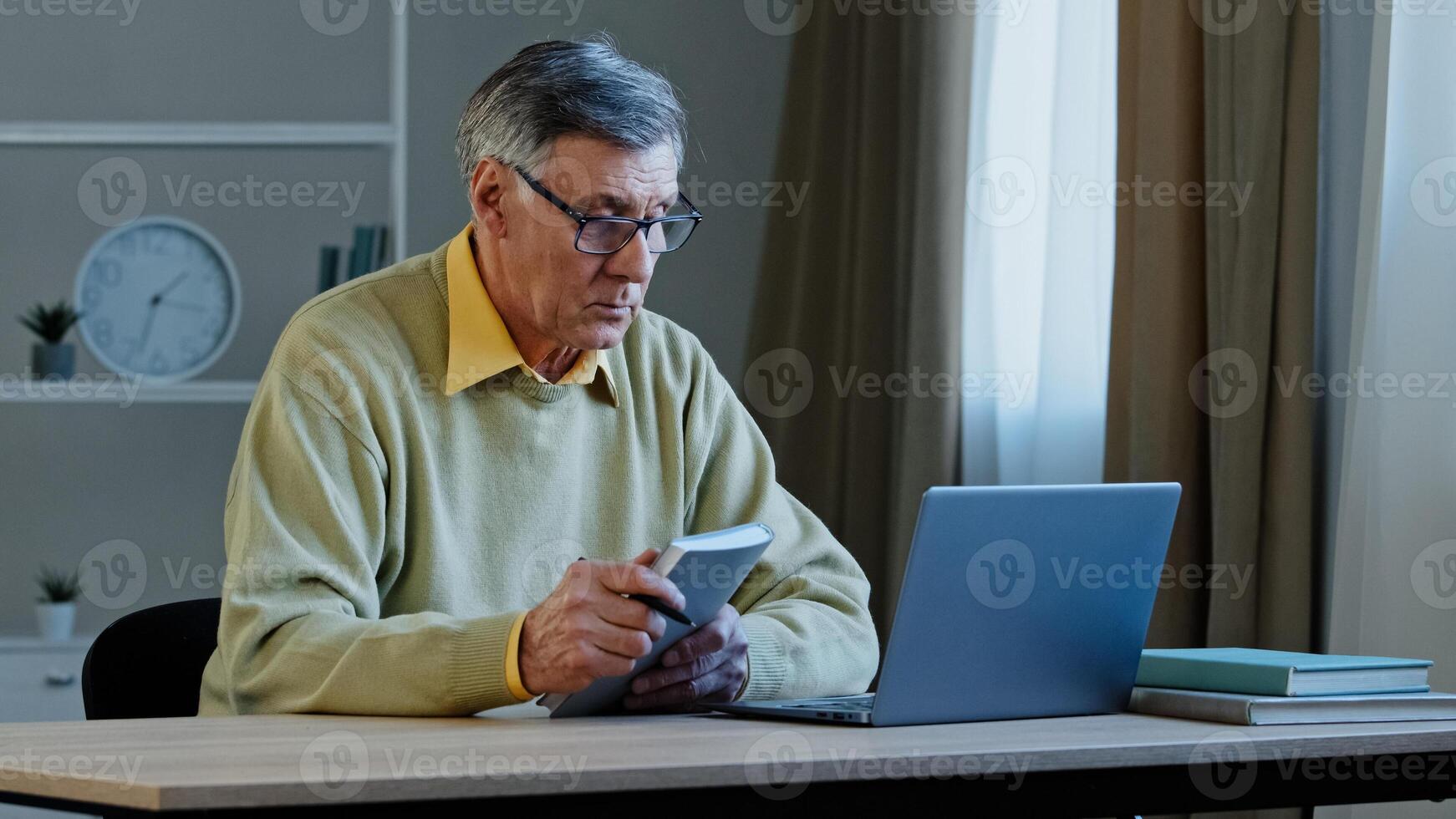 Caucasian old man teacher with notebook talking in webcam remote learning conference call leading webinar class lecture for university students from home quarantine 60s businessman online chat photo