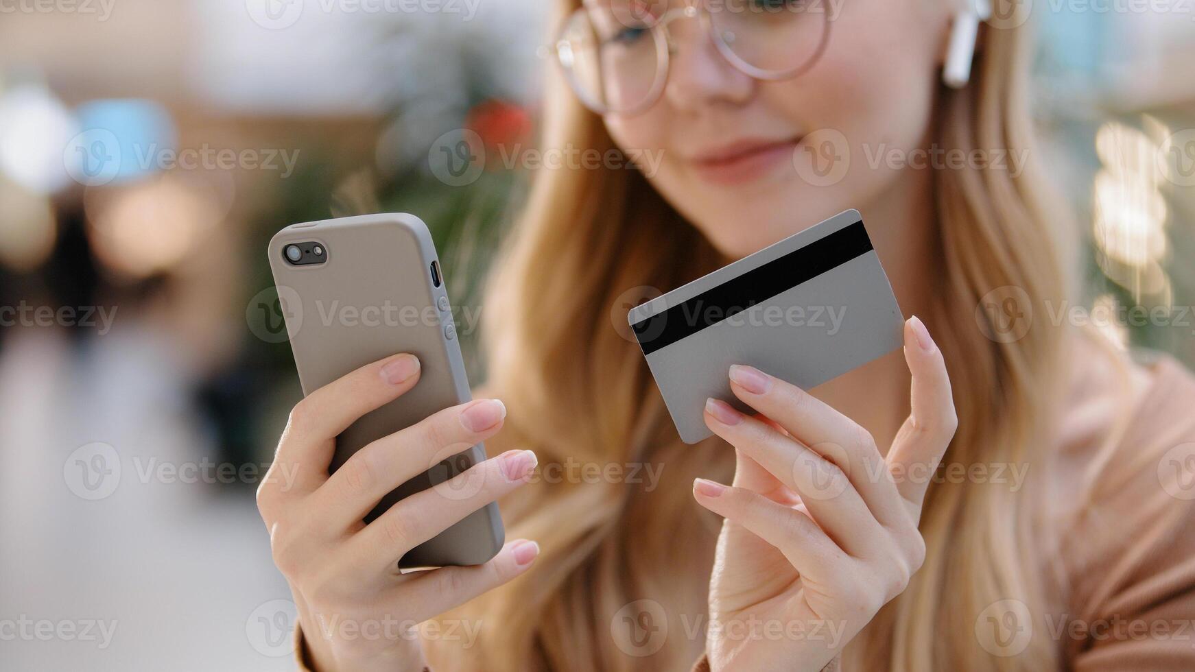 Close-up young girl hands holding smartphone and credit card happy woman customer make online purchase pay bills using banking app on phone virtual remote shopping successful safe transaction concept photo