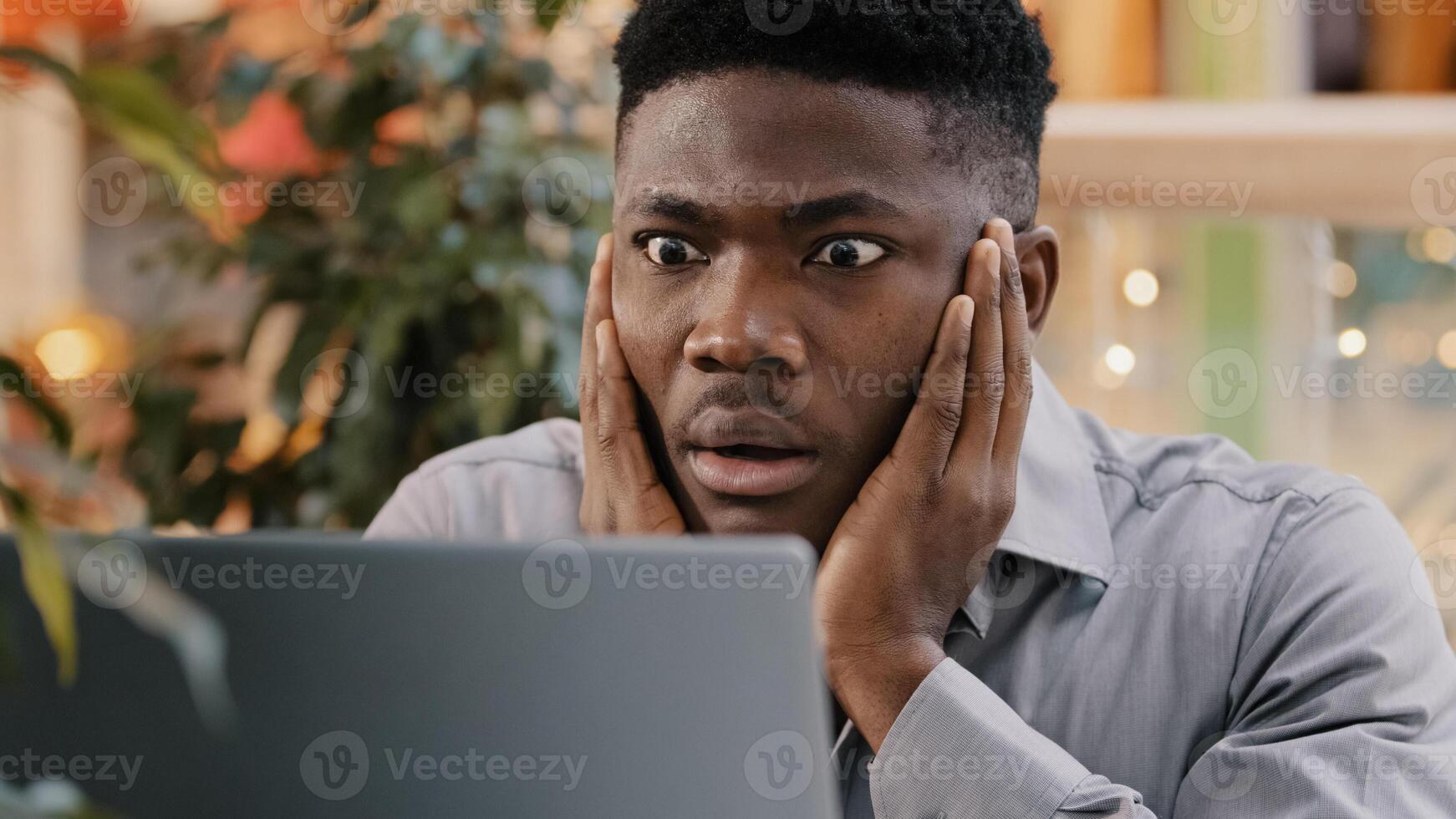 Close-up young businessman looking at laptop screen getting bad news surprised shocked man holding head found error incorrectness in electronic document virus in application loss important information photo