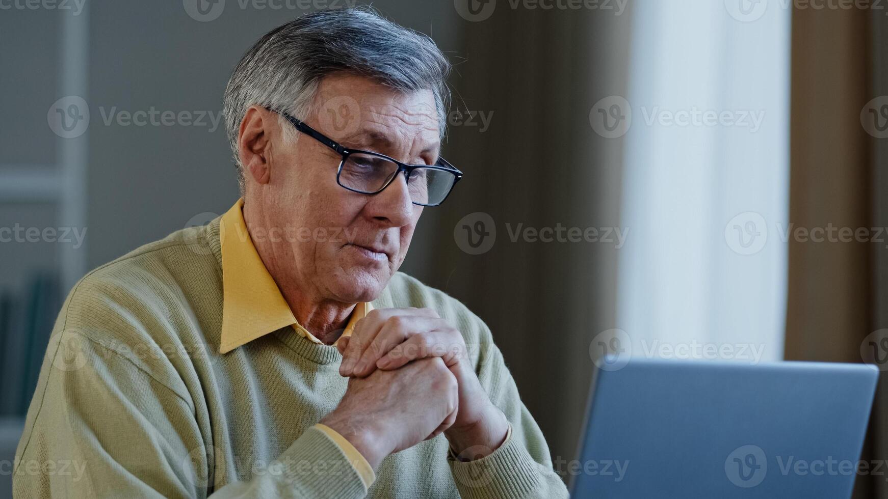 Old Caucasian man elderly mature senior businessman worker entrepreneur grandfather at office at home at table with laptop working thinking idea pensive think about online project work with computer photo