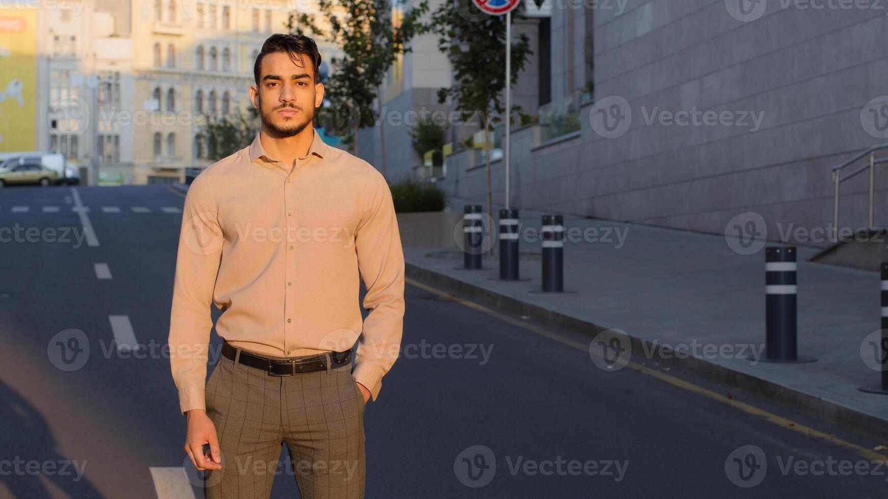 Hispanic handsome young business man arabic bearded manager worker boss leader guy entrepreneur in formal clothes stands in city street background posing confidently looking at camera photo