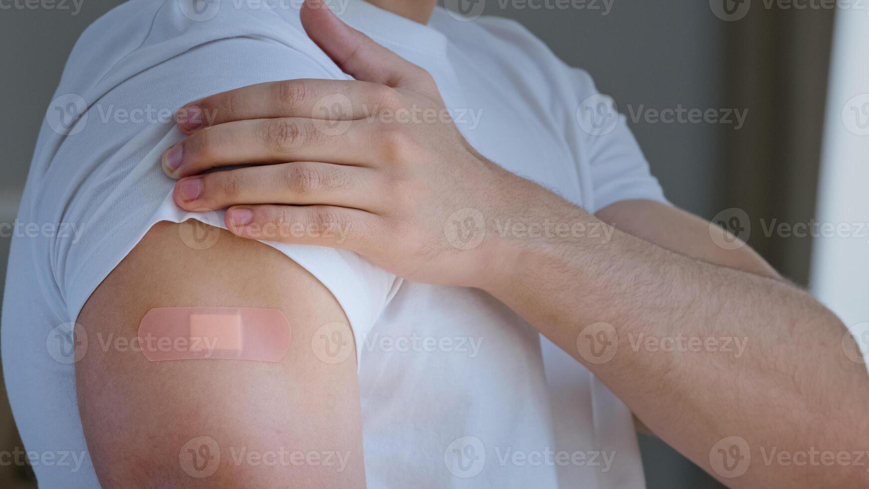 Cropped shooting arabian young man, portrait male Spaniard ethnic guy patient looking at shoulder with medical plaster on mark of injection smiling satisfied vaccination immunization against covid photo