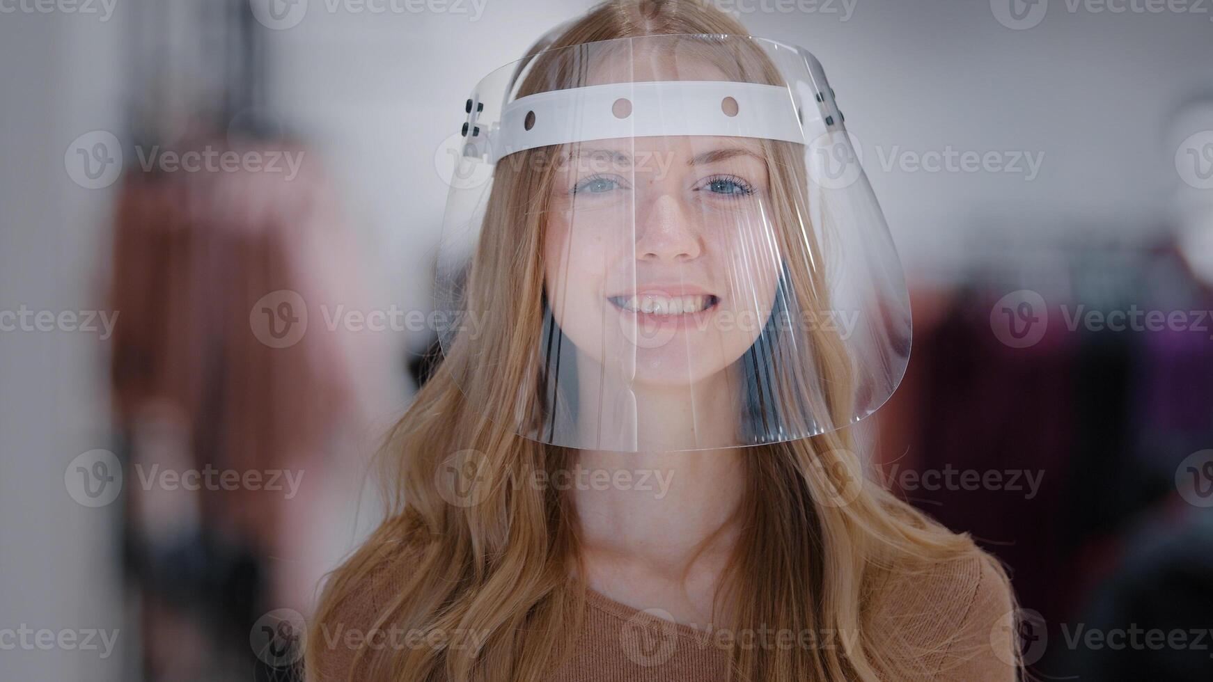 Headshot portrait girl in transparent plastic mask close-up young caucasian woman smiling looking at camera protection from infection coronavirus personal protective equipment pandemic control concept photo