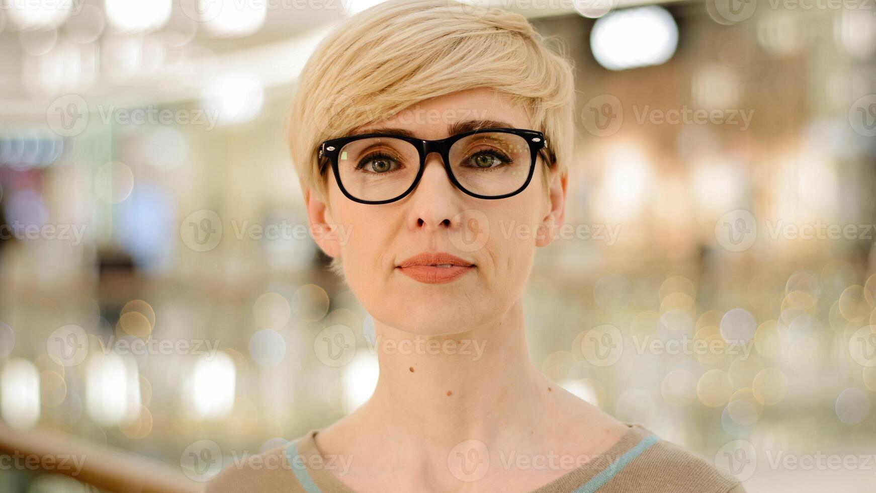 Close-up middle-aged adult lady in glasses looking at camera poor vision problems with eyesight. Portrait caucasian business woman female specialist professional in corporate space looking at camera photo