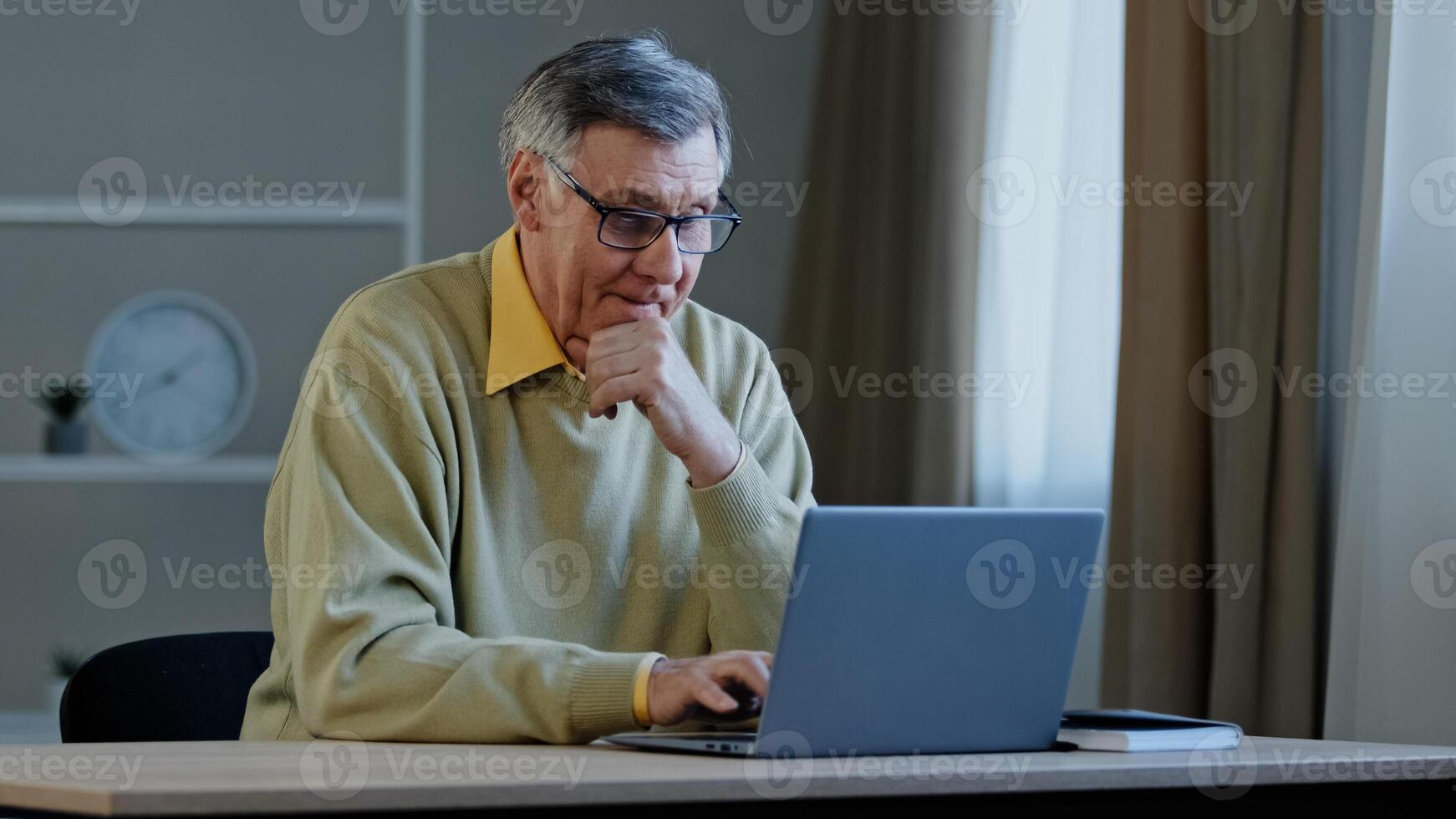 Old Caucasian man with computer work indoors. Elderly mature senior businessman worker entrepreneur grandfather at office at home at table with laptop working thinking pensive think online project photo