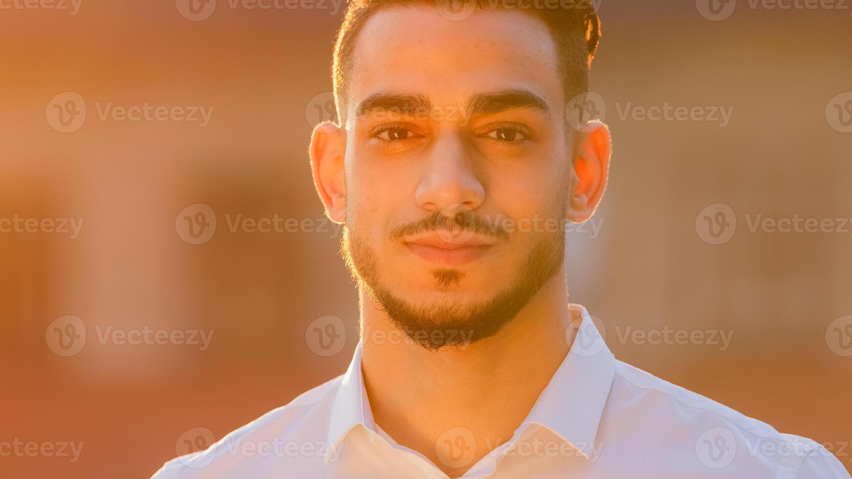 Portrait outdoors arabic hispanic spaniard business man boss leader guy businessman wears white shirt standing outside looking at camera posing at sunset sunbeams sunshine. Close-up friendly male face photo