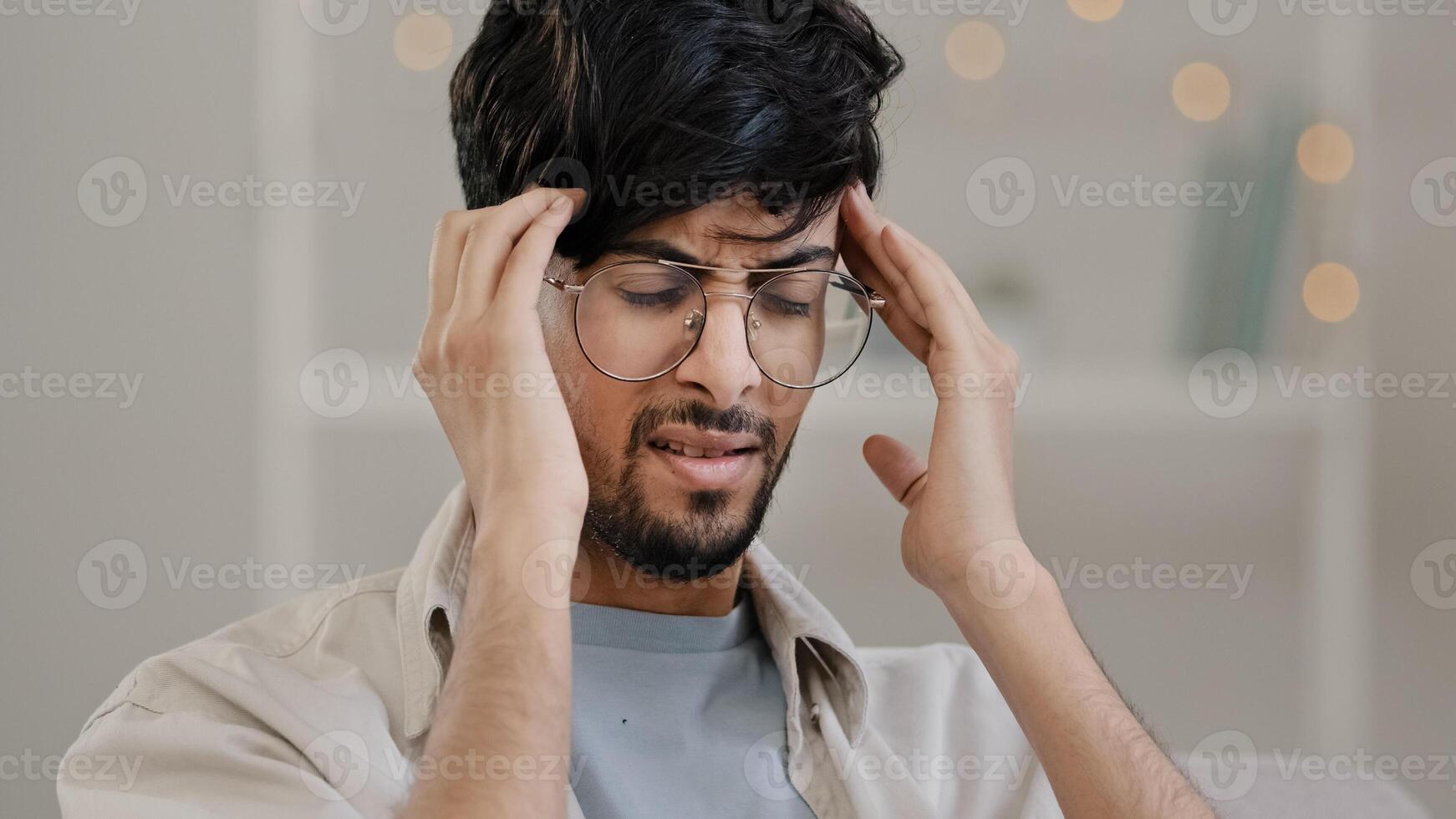 Close-up arabic man bearded guy with glasses feels stress overwork cranial pressure massages weight on head suffering from headache migraine sighing heavily illness feeling unwell panic attack problem photo