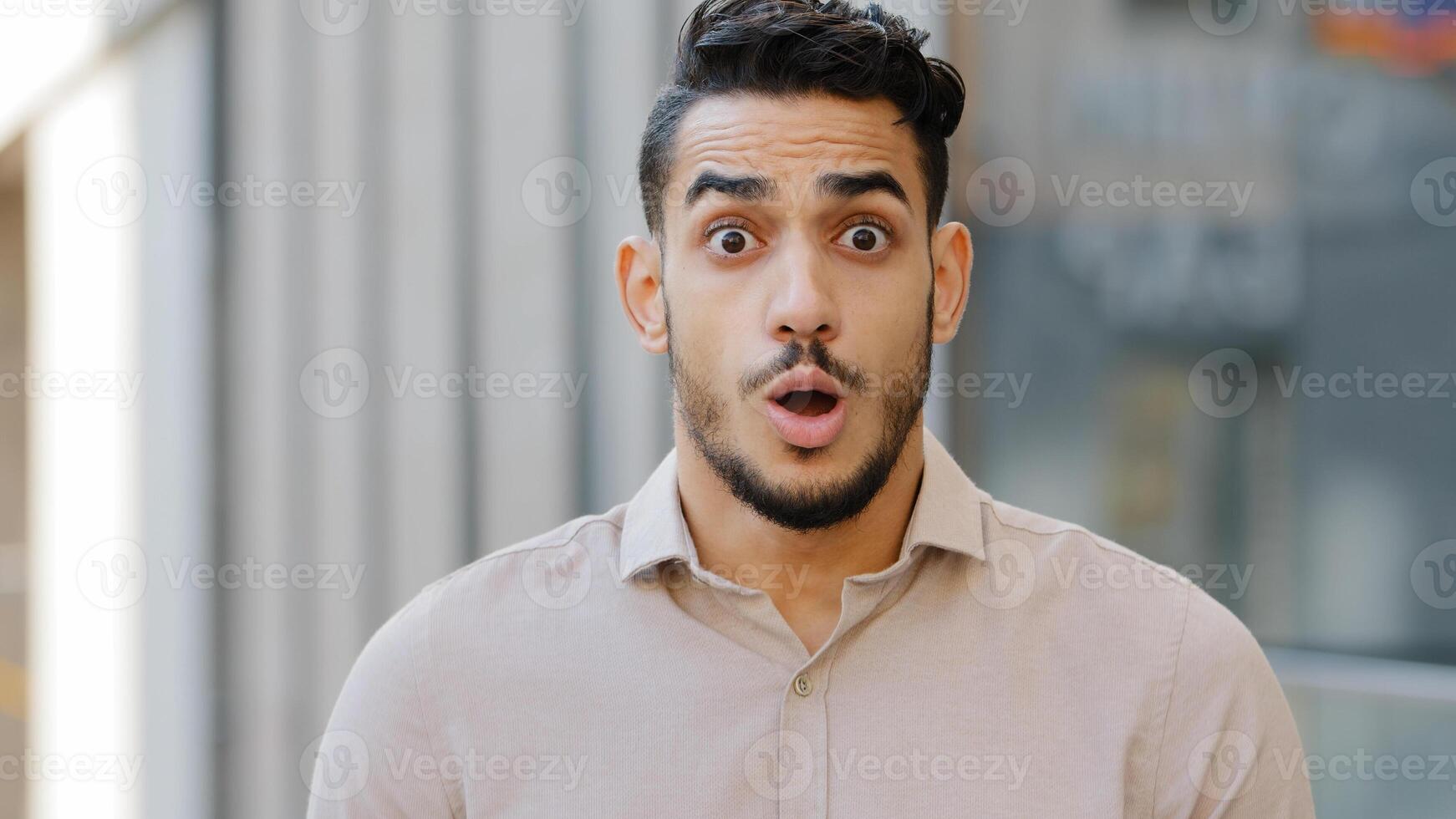 Portrait of hispanic arabian shocked bearded business man entrepreneur looking at camera opens mouth wide in surprise of unexpected news shouts. Close-up guy with expression of horror fear shock photo