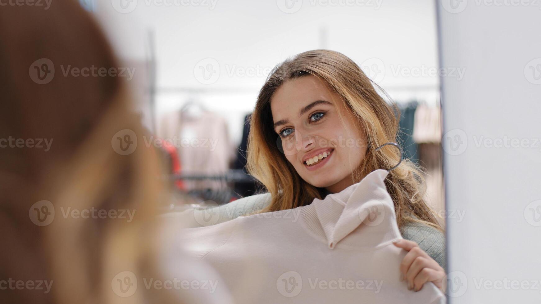 Cheerful carefree happy young girl shopper shopaholic woman smiling lady consumer female blonde trying on new sweater clothes in store at home near mirror shopping beauty discounts trending style photo