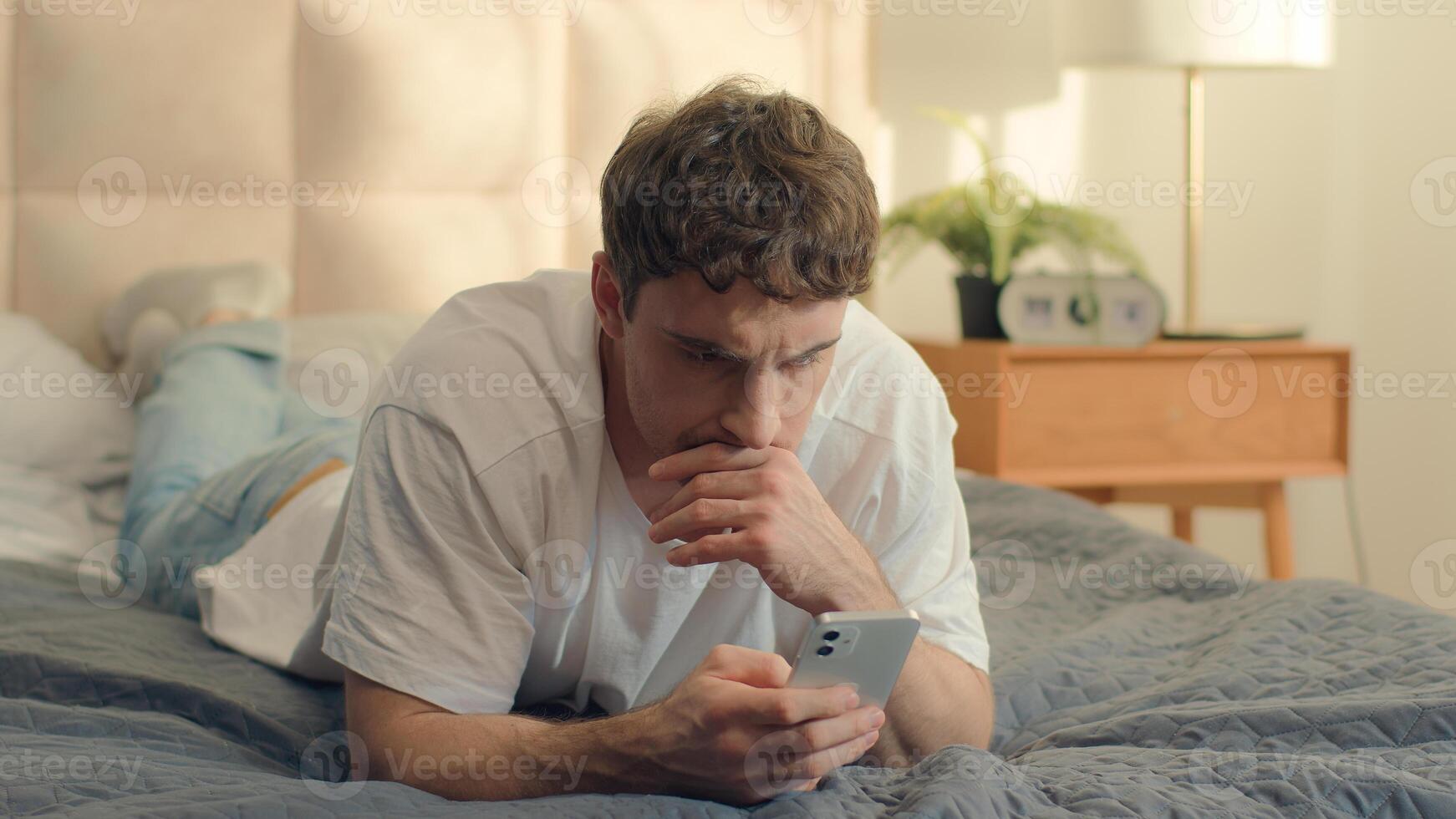 Serious Caucasian man bed using mobile phone smartphone guy male technology pensive problem frown error rejection fail broken gadget spam connection notification stressful worry wrong trouble banking photo