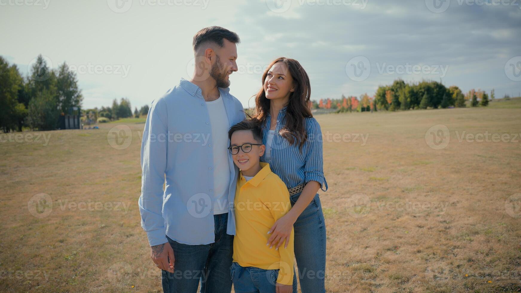 Happy Caucasian farmers family portrait smiling married father mother son little kid child boy hugging together outside countryside field. Agronomy ecology parenting enjoy relaxation fresh air nature photo