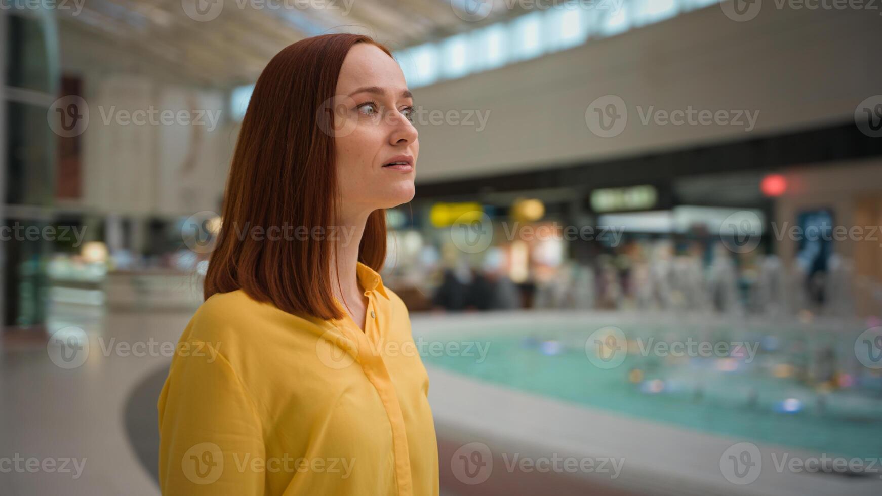 Amazed smiling young Caucasian redhead girl woman female tourist businesswoman traveler looking around shopping mall surroundings amazement admiring enjoying weekend indoor modern entertainment center photo