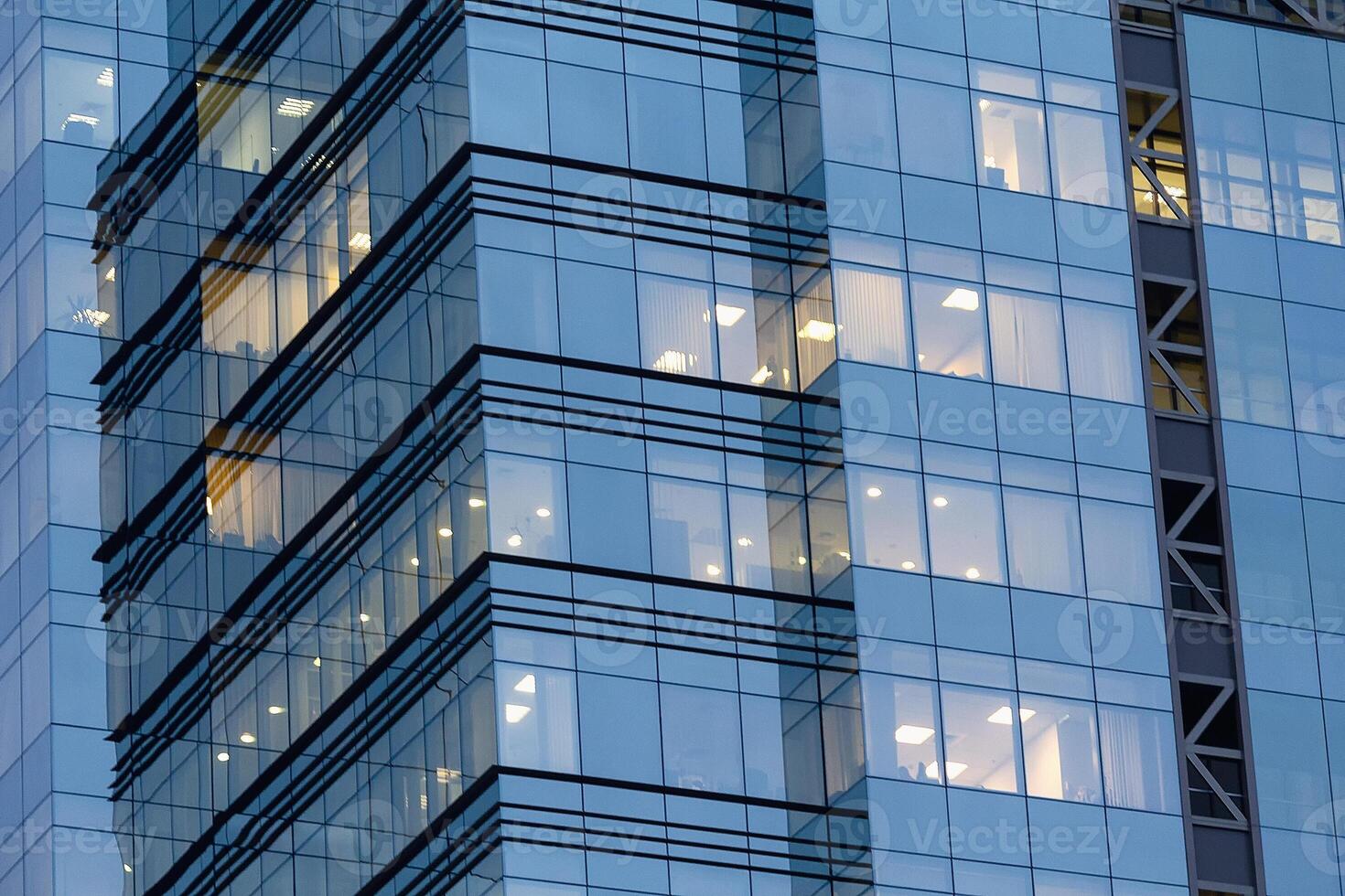 Office windows lights, high-rise glass skyscraper business building in city downtown, work non-stop, turn on and off photo