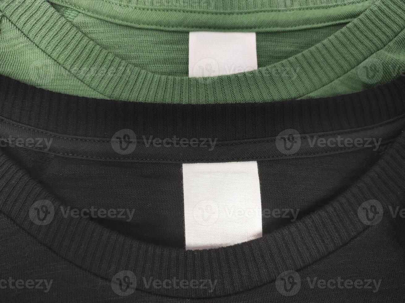 Two cotton T-shirts black and green with a blank white label indicating the size of the clothes and washing instructions photo