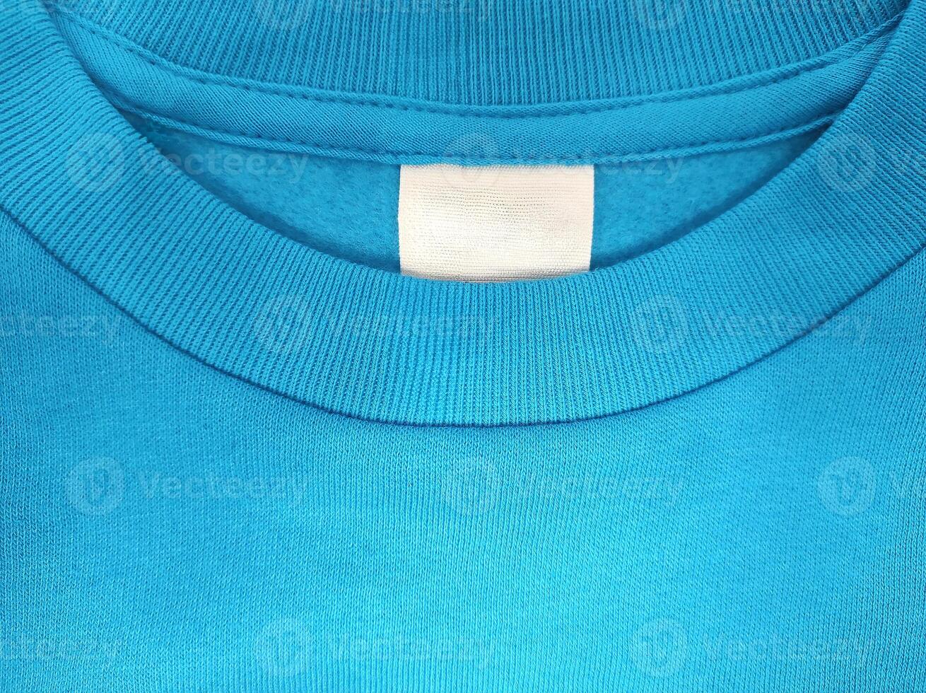 Blank white label for clothing size and washing on blue background of t-shirt fabric texture photo