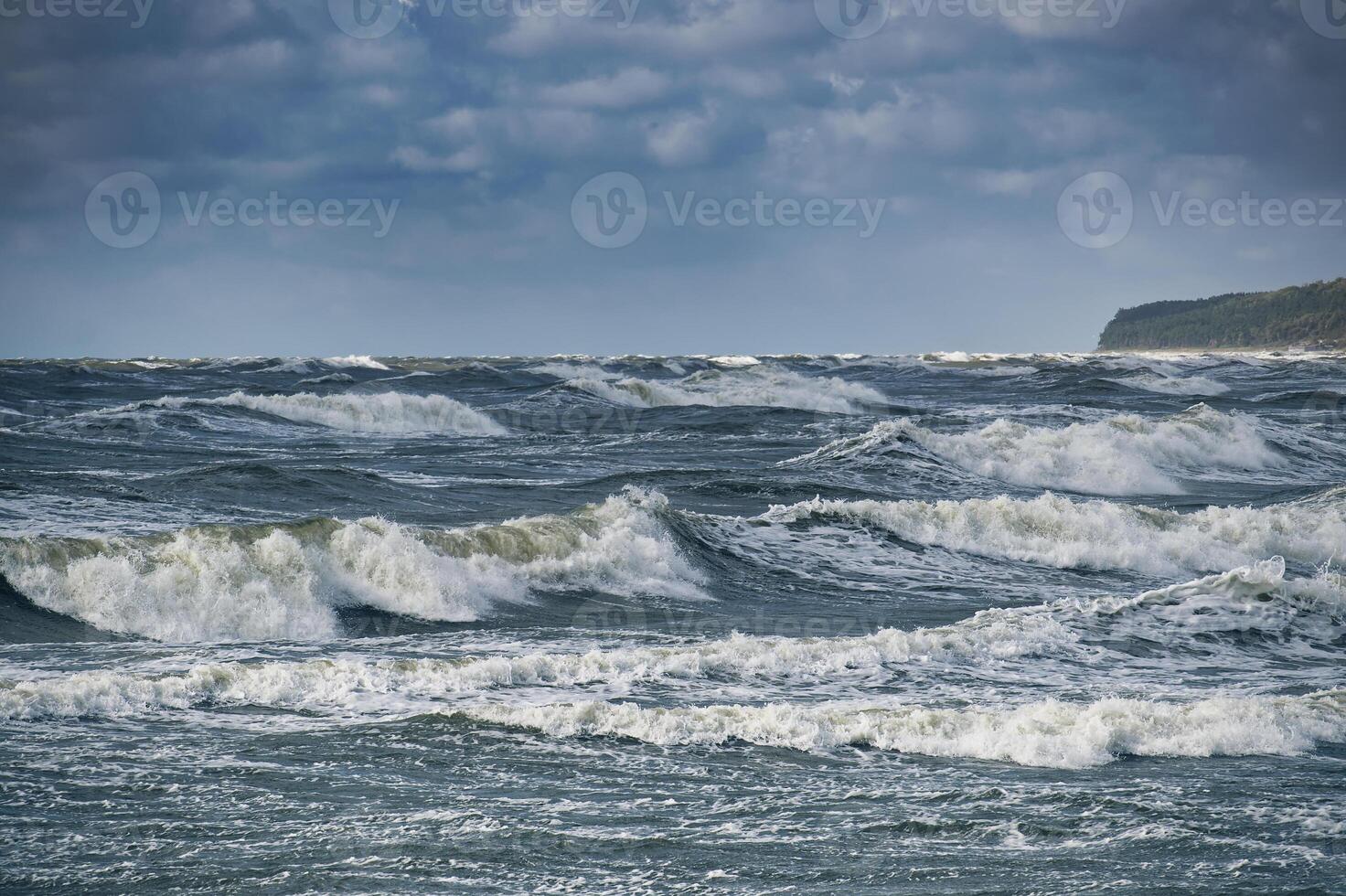 Dramatic ocean waves crashing against the shore under a cloudy sky photo