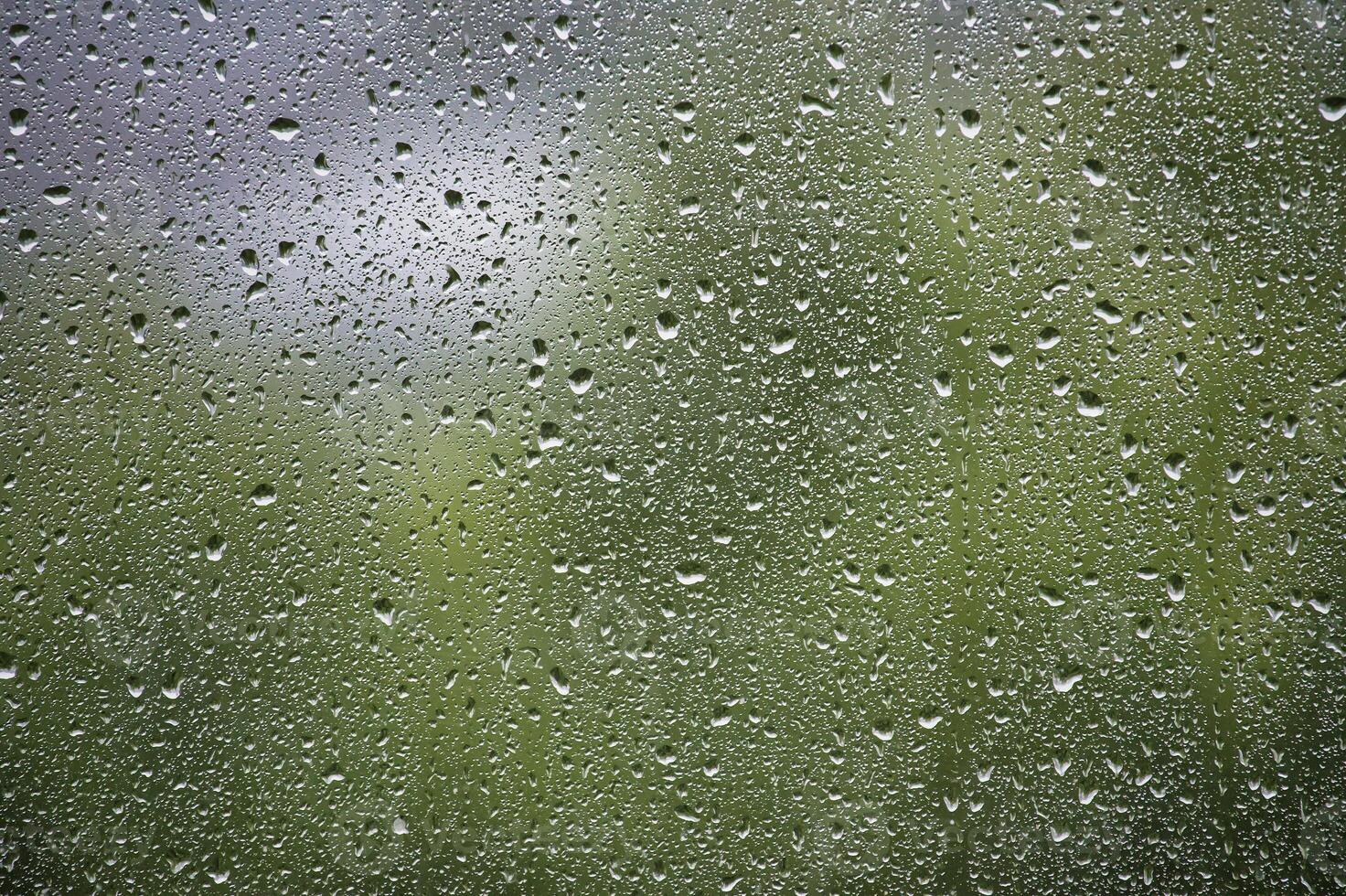 Window surface covered with many water droplets of various sizes, creating a textured pattern photo