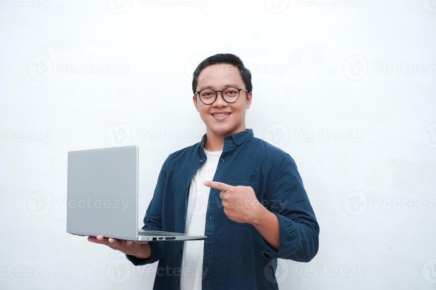 Asian man with blue shirt holding a laptop and smiling to camera. Concept of student or business man. isolated on white background photo