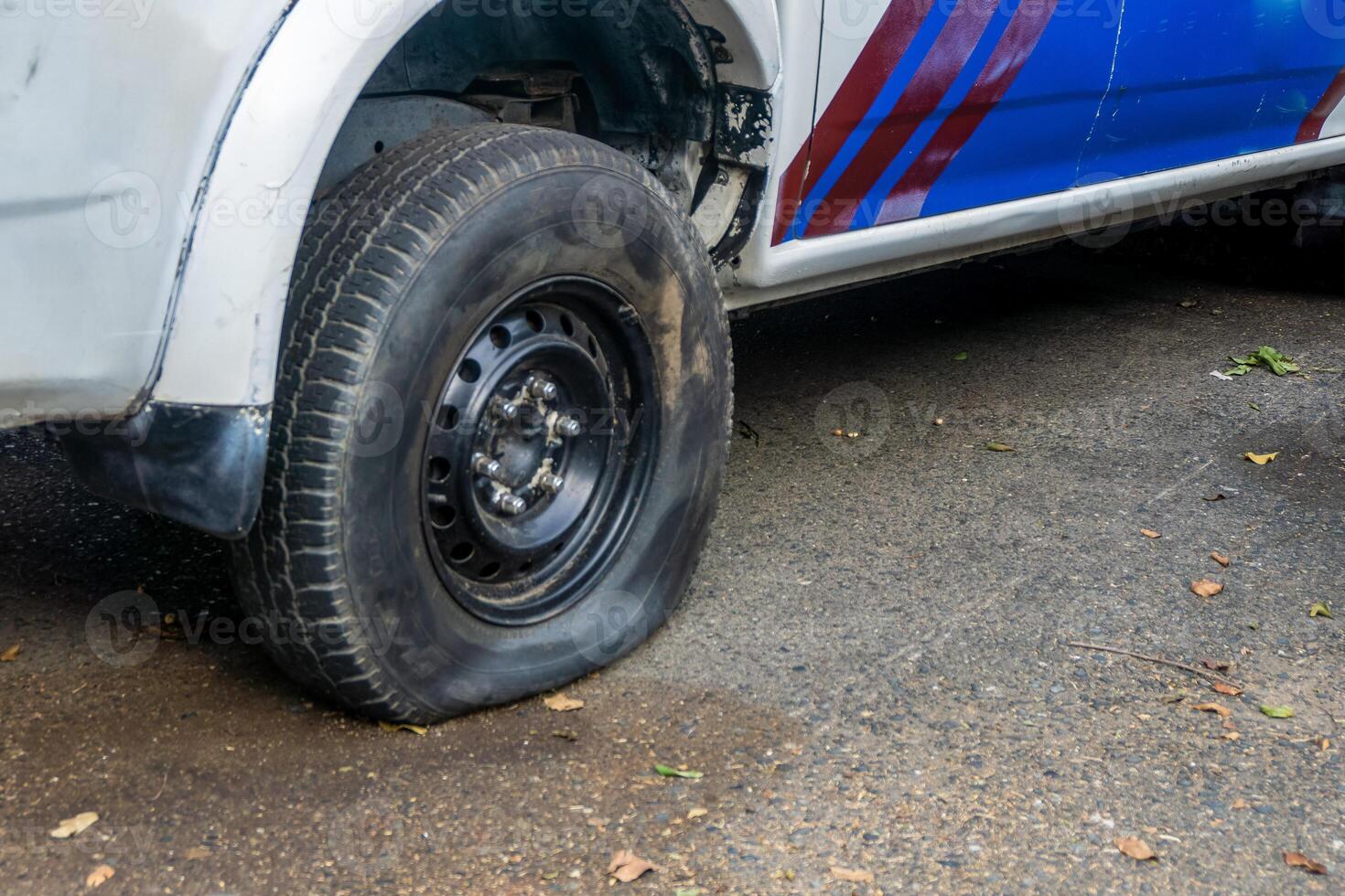 Close up of back right flat tire of car. Leak air pressure in a car tire. Car stand on the road because of tire losing air pressure. photo