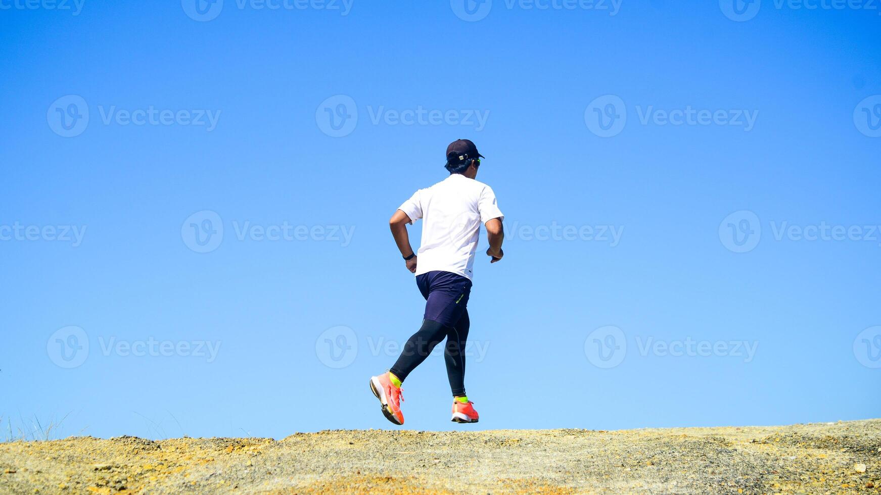 Man Running Outdoors on a Sunny Day with Clear Blue Sky in the Background photo