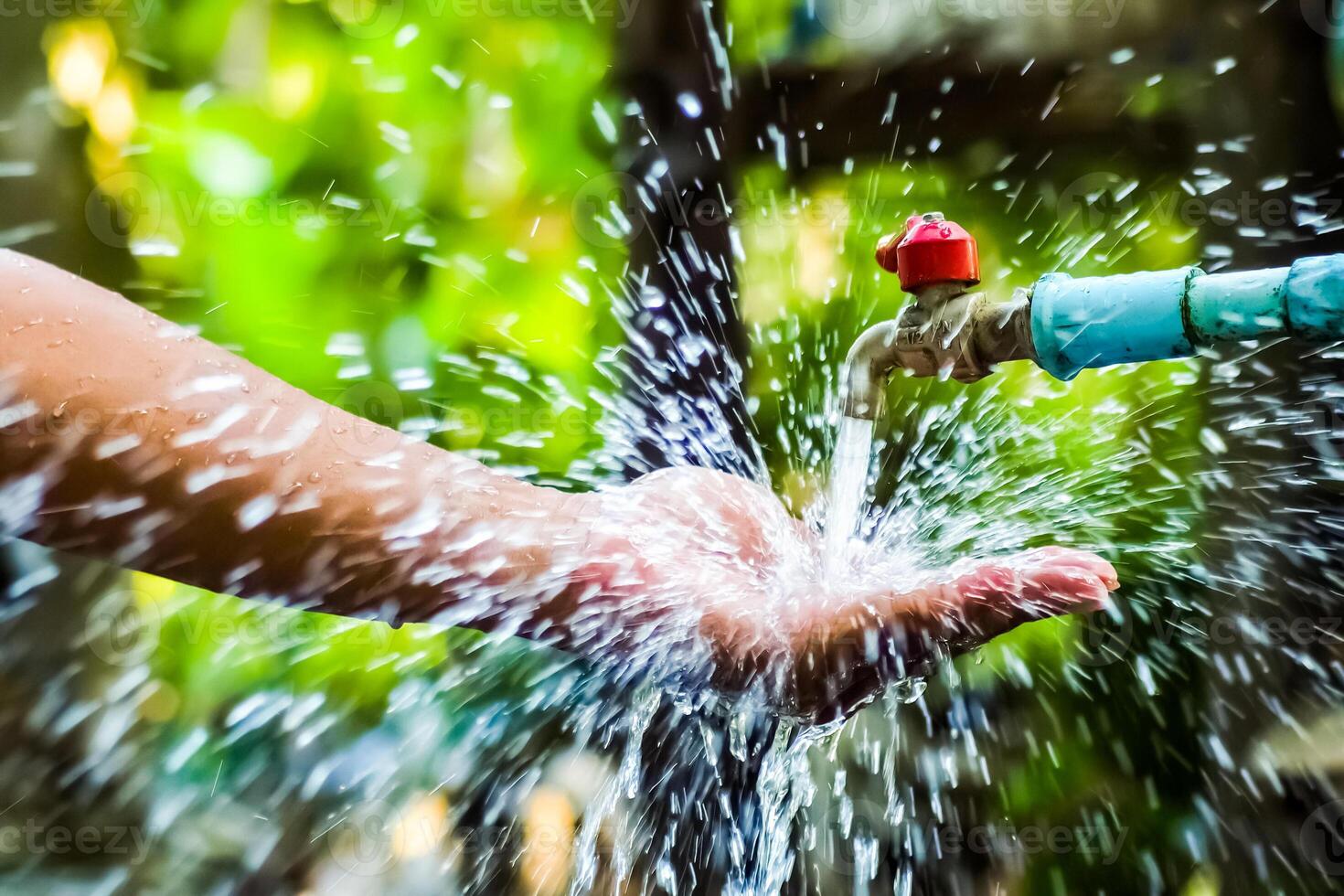 Refreshing Splash of Water from Outdoor Faucet in Lush Green Garden on a Sunny Day photo