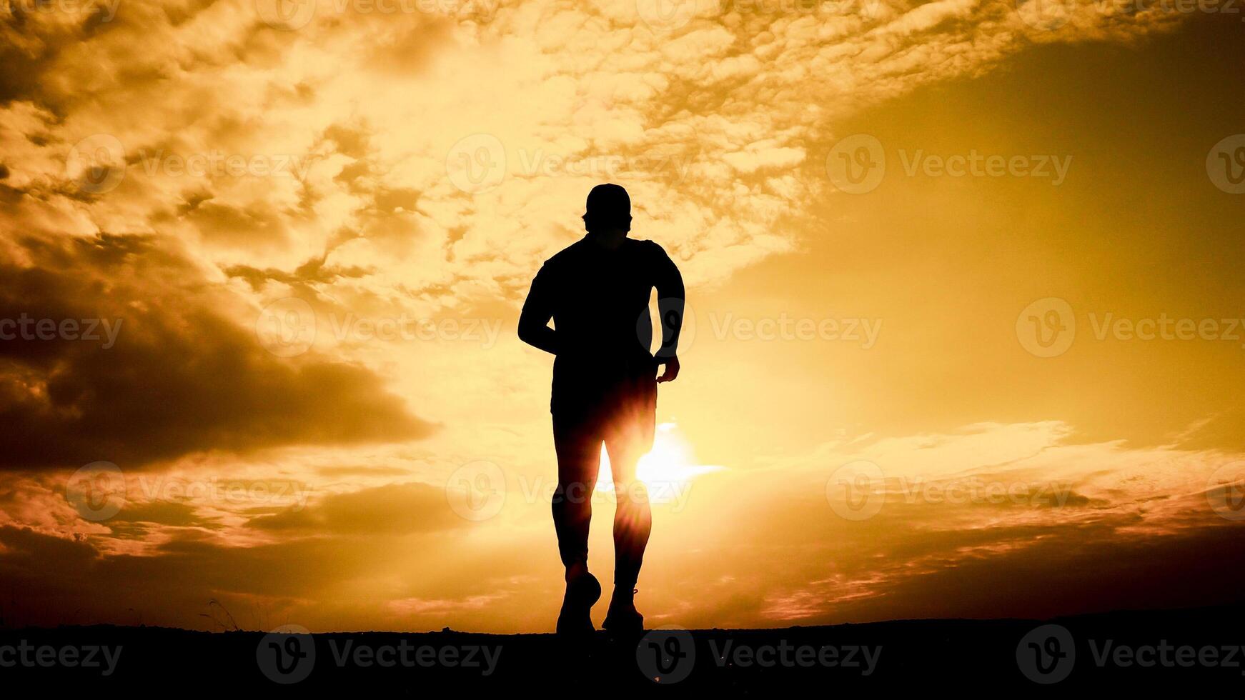 Silhouette of a Man Running at Sunset with Dramatic Sky and Golden Light in the Background photo