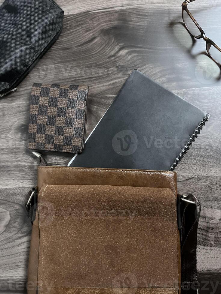 Leather bag with gadgets and notebooks on Wooden Work Desk photo