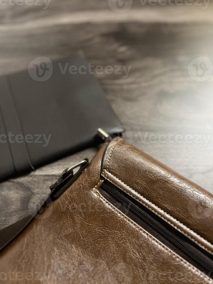 Leather bag with gadgets and notebooks on Wooden Work Desk photo