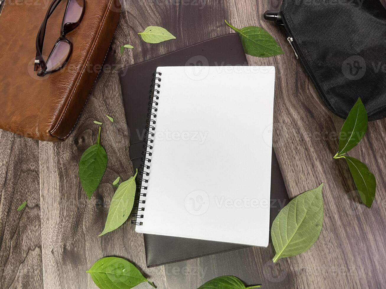 Still life photography blank notebook on wooden table with a cup of coffee, plant, leaf on table photo