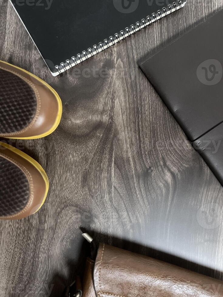 Leather bag with gadgets and notebooks on Wooden Work Desk photo